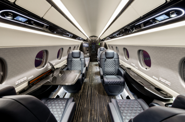 Interior of a modern airplane cabin with cushioned seats, tables, and large windows