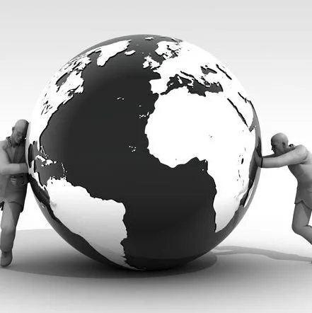 Two people are pushing opposite sides of a large globe of the Earth.