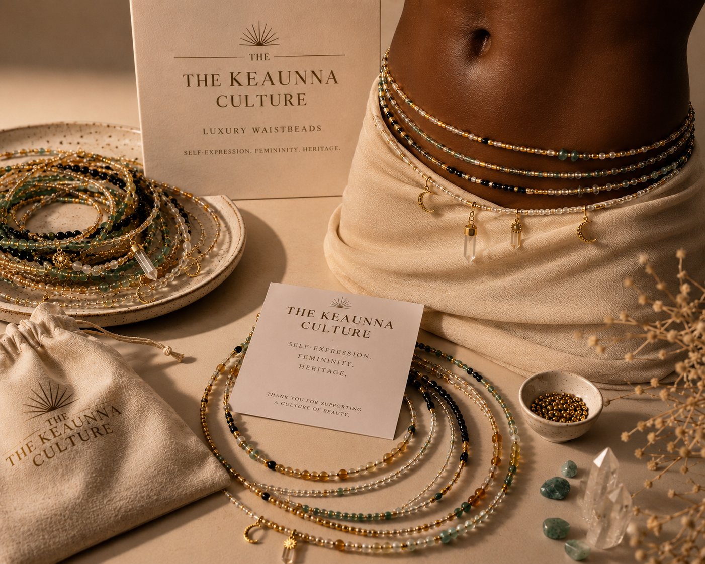 Display of jewelry, including layered necklaces with beads and pendants, arranged on a neutral fabric surface along with promotional cards and pouches for The Keaunda Culture, which specializes in luxury waist beads.