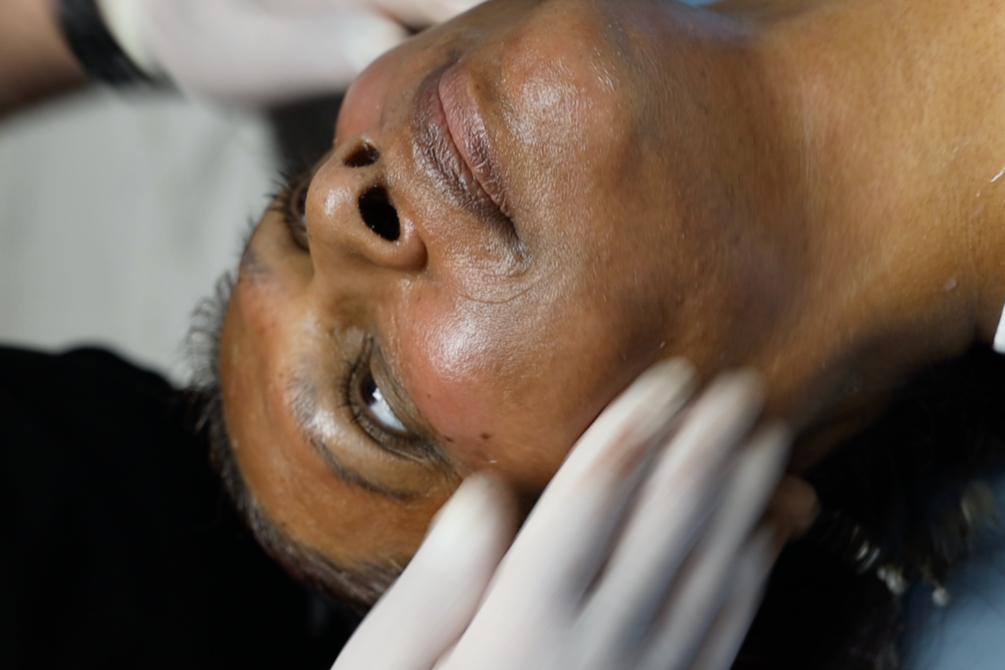 Close-up of a person's face lying down with eyes open, showing skin details and facial features.