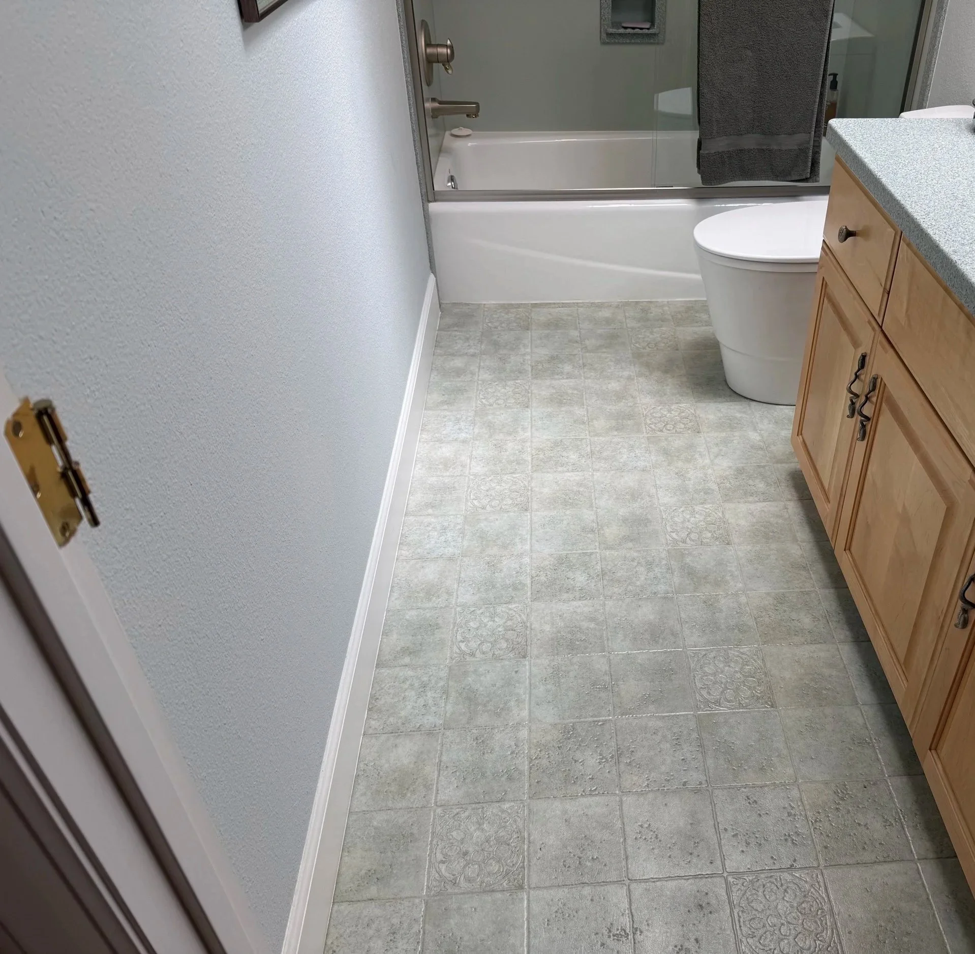 Bathroom before renovation with existing patterned vinyl flooring and wood vanity
