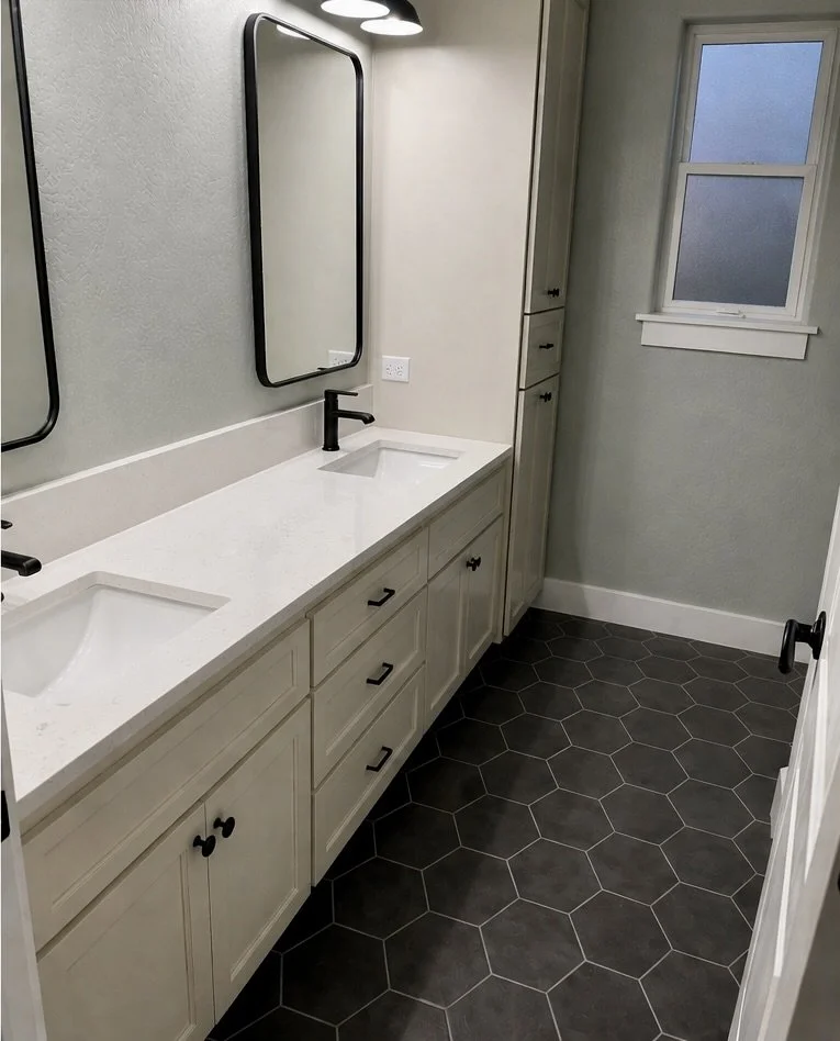 Remodeled bathroom with black hexagon tile floor, double vanity and black fixtures in Southern Oregon.