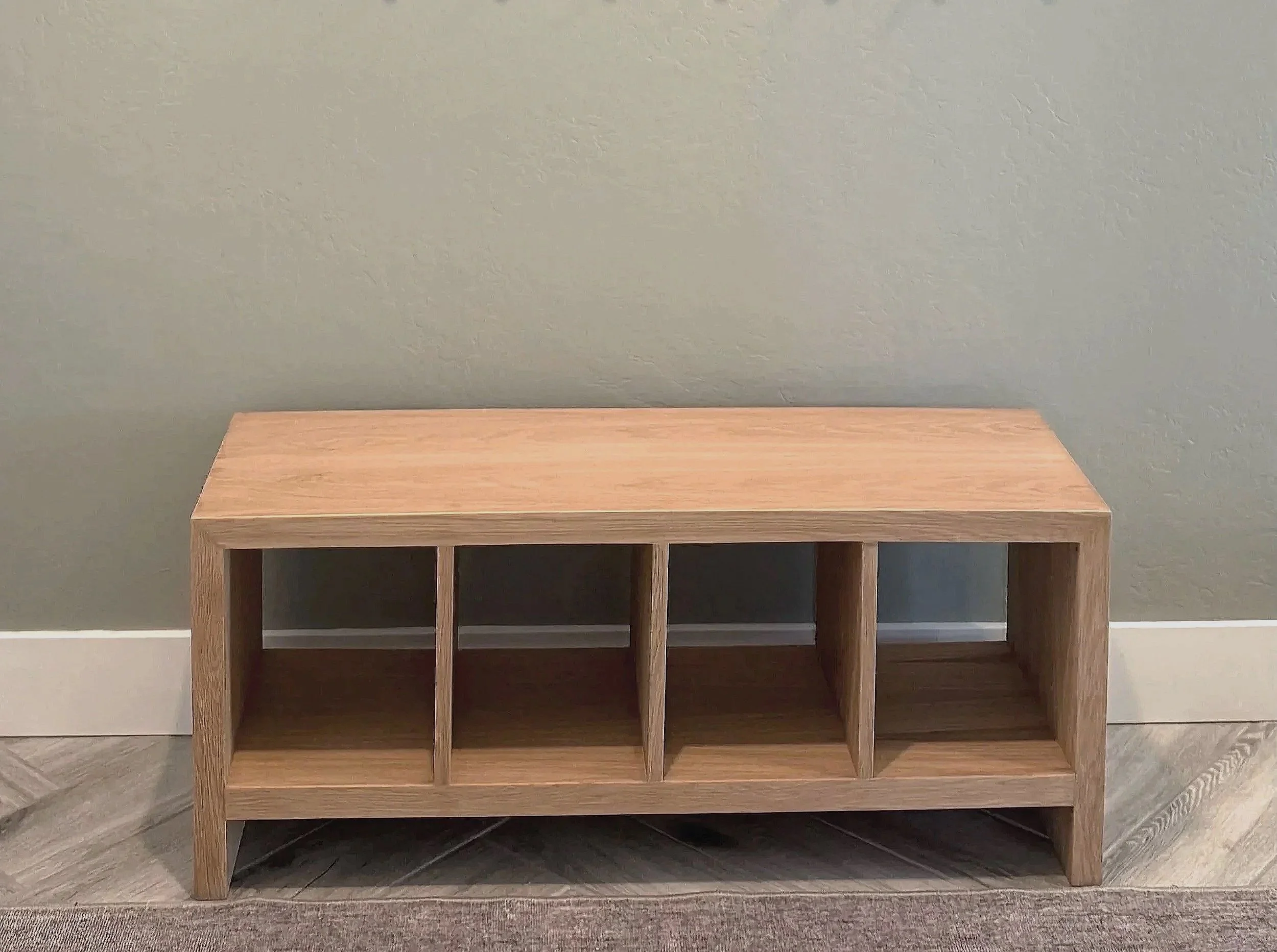 Front view of a custom white oak entry bench with four open shoe cubbies.