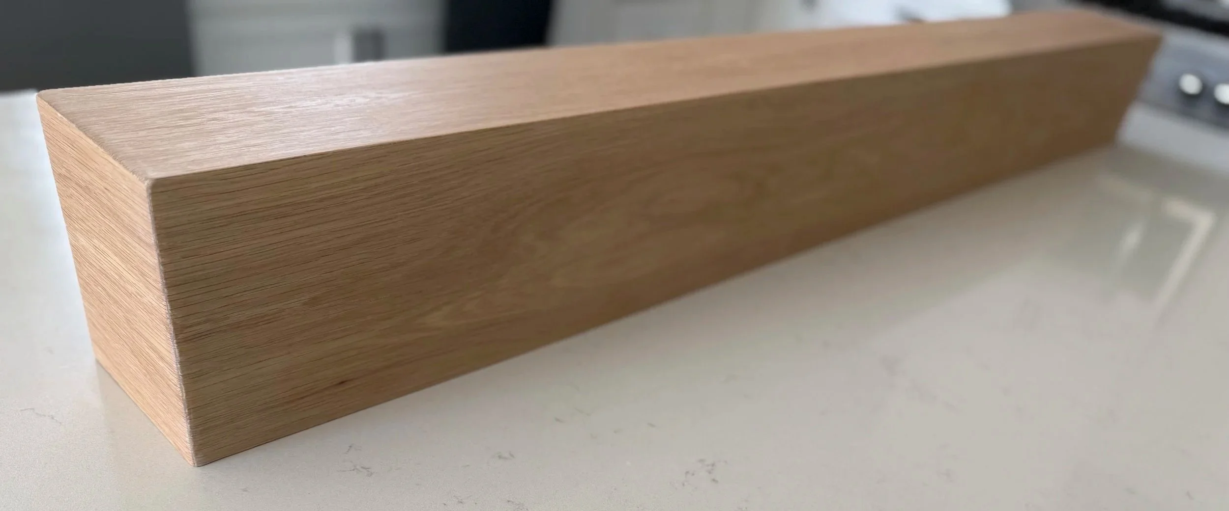 Close-up of handcrafted white oak mantel with mitered corner and natural wood grain
