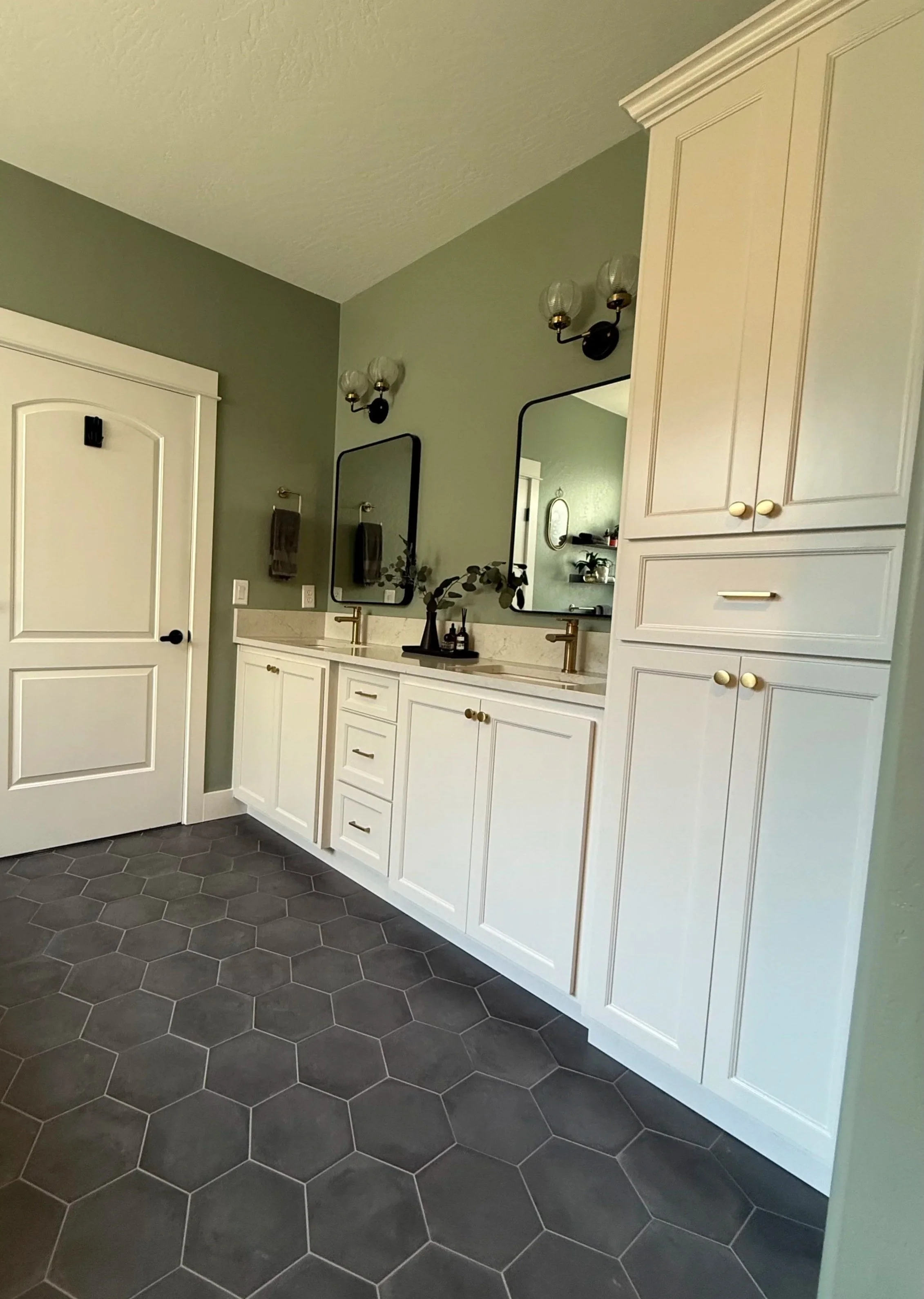 Remodeled primary bathroom vanity with white cabinetry, charcoal hex tile flooring and modern fixtures.