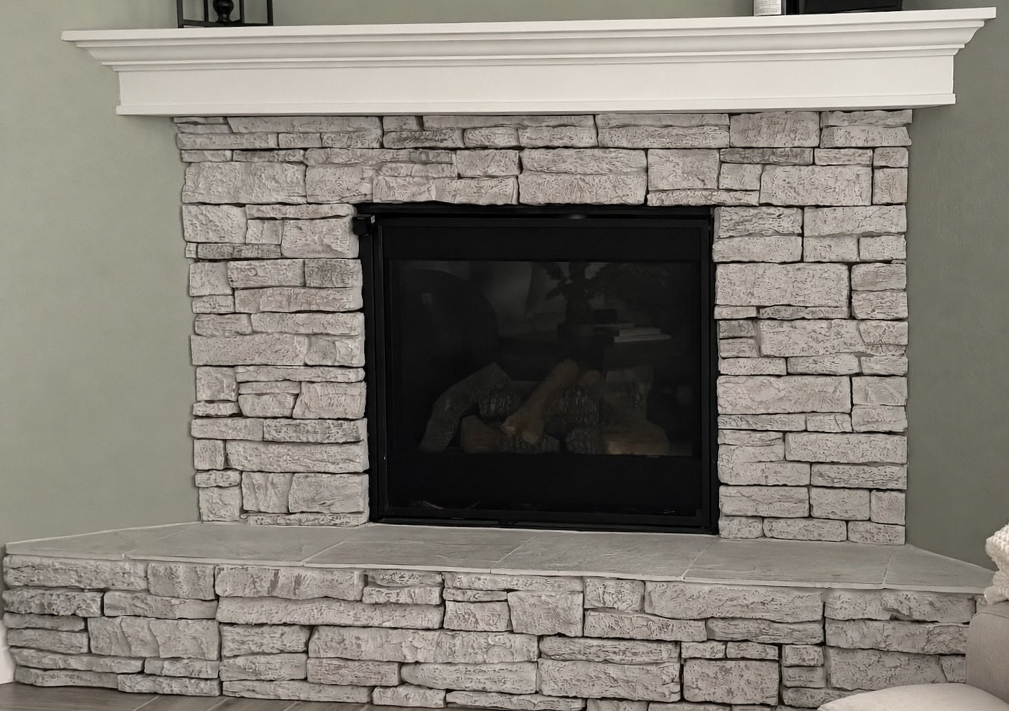 Corner fireplace with stacked stone surround before fireplace remodel