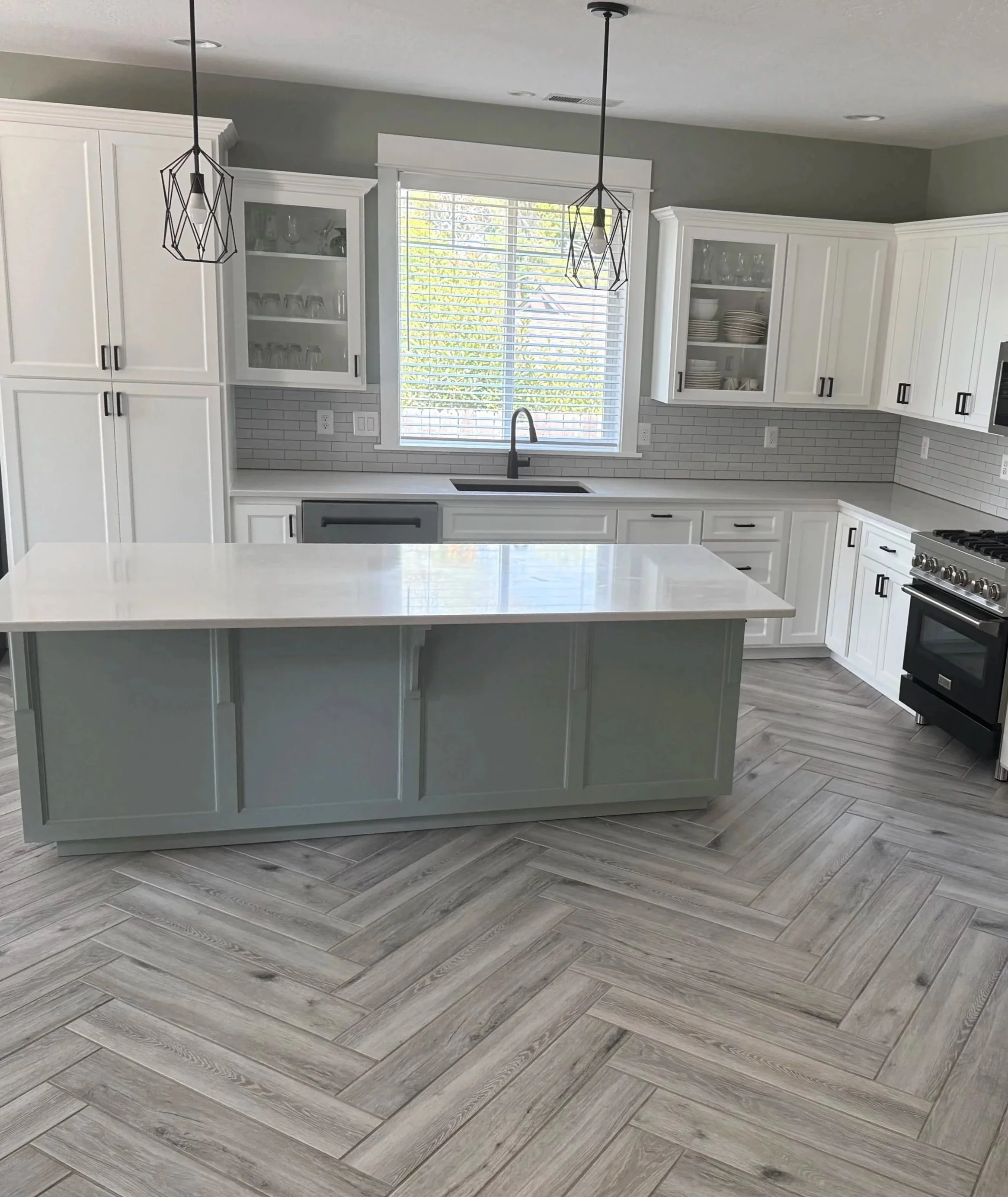 Remodeled kitchen with painted cabinetry, quartz countertops and herringbone porcelain tile flooring.
