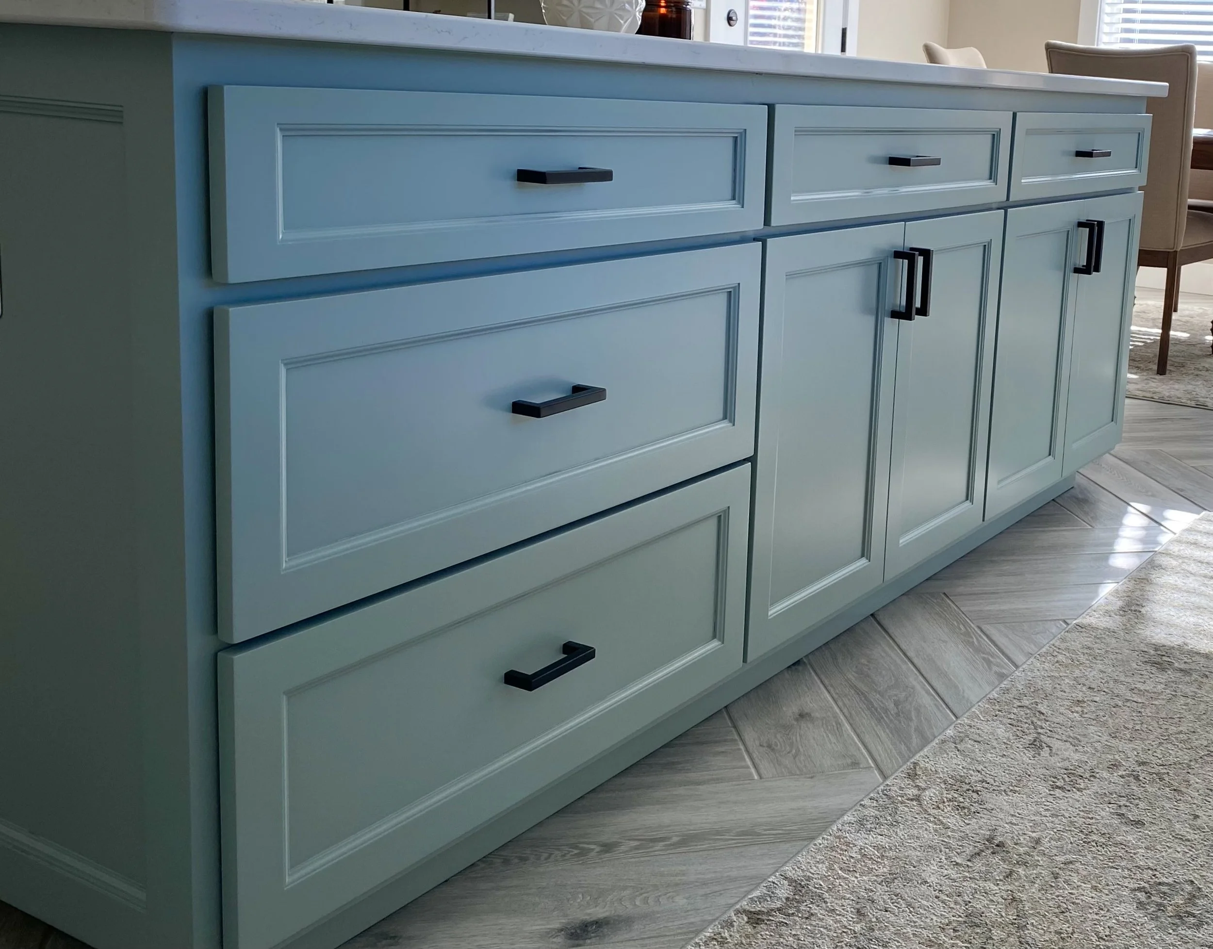 Remodeled kitchen island with painted cabinetry, quartz countertop and herringbone porcelain tile flooring.