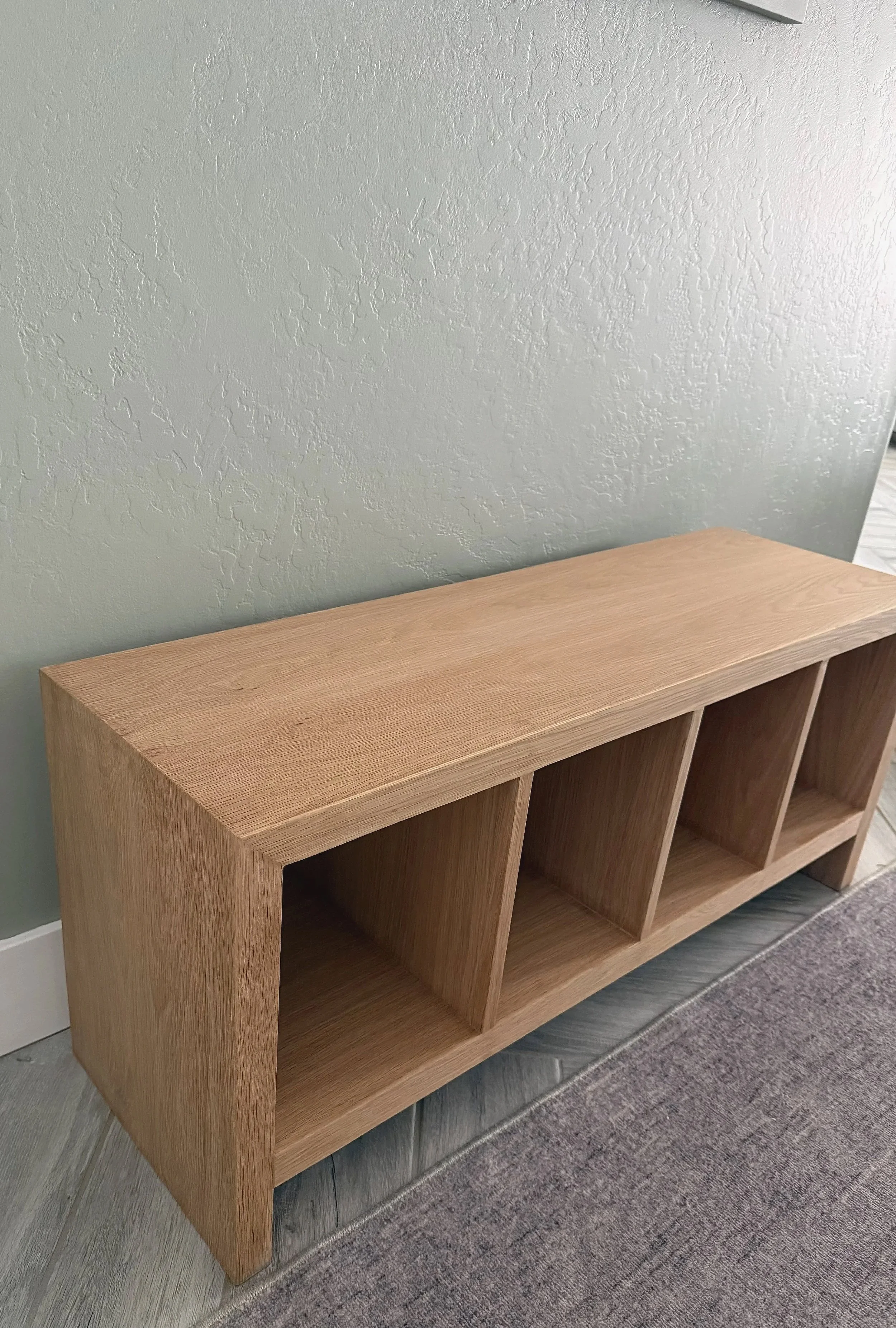 Angled view of a handcrafted white oak entry bench with mitered corners and a clear matte finish.