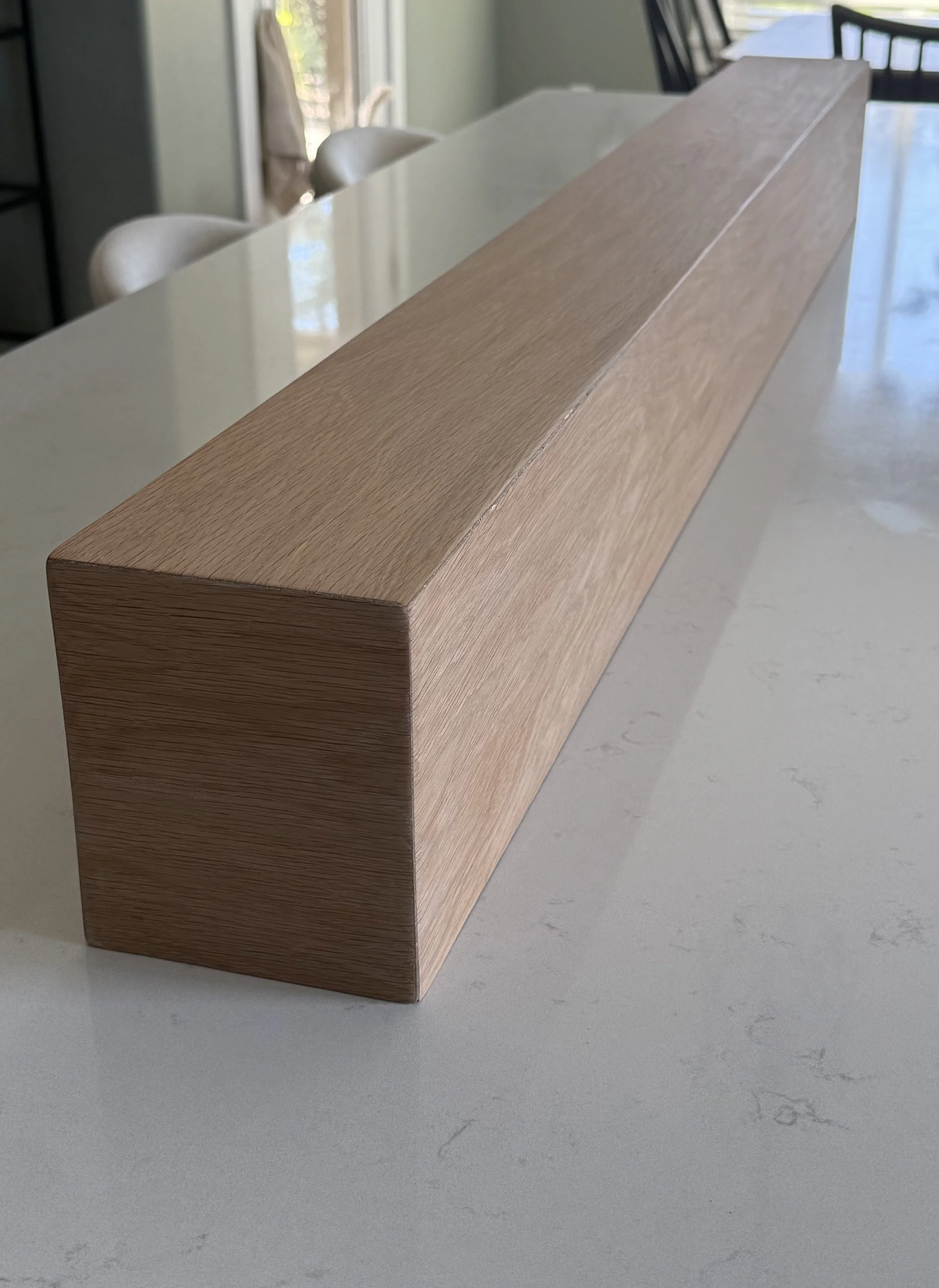 Close-up of handcrafted white oak mantel with mitered corner and natural wood grain