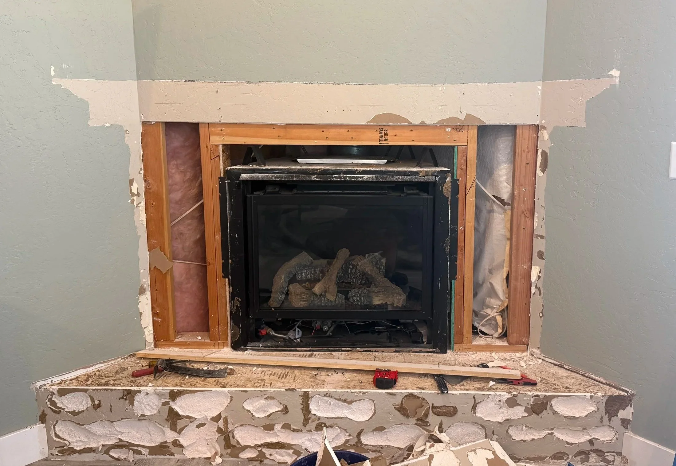 Corner fireplace during demolition with original stone surround removed