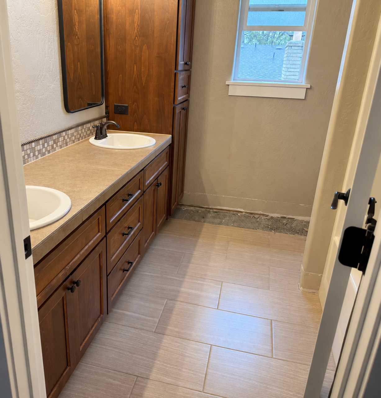 Guest bathroom before remodel with wood cabinetry and beige tile flooring.