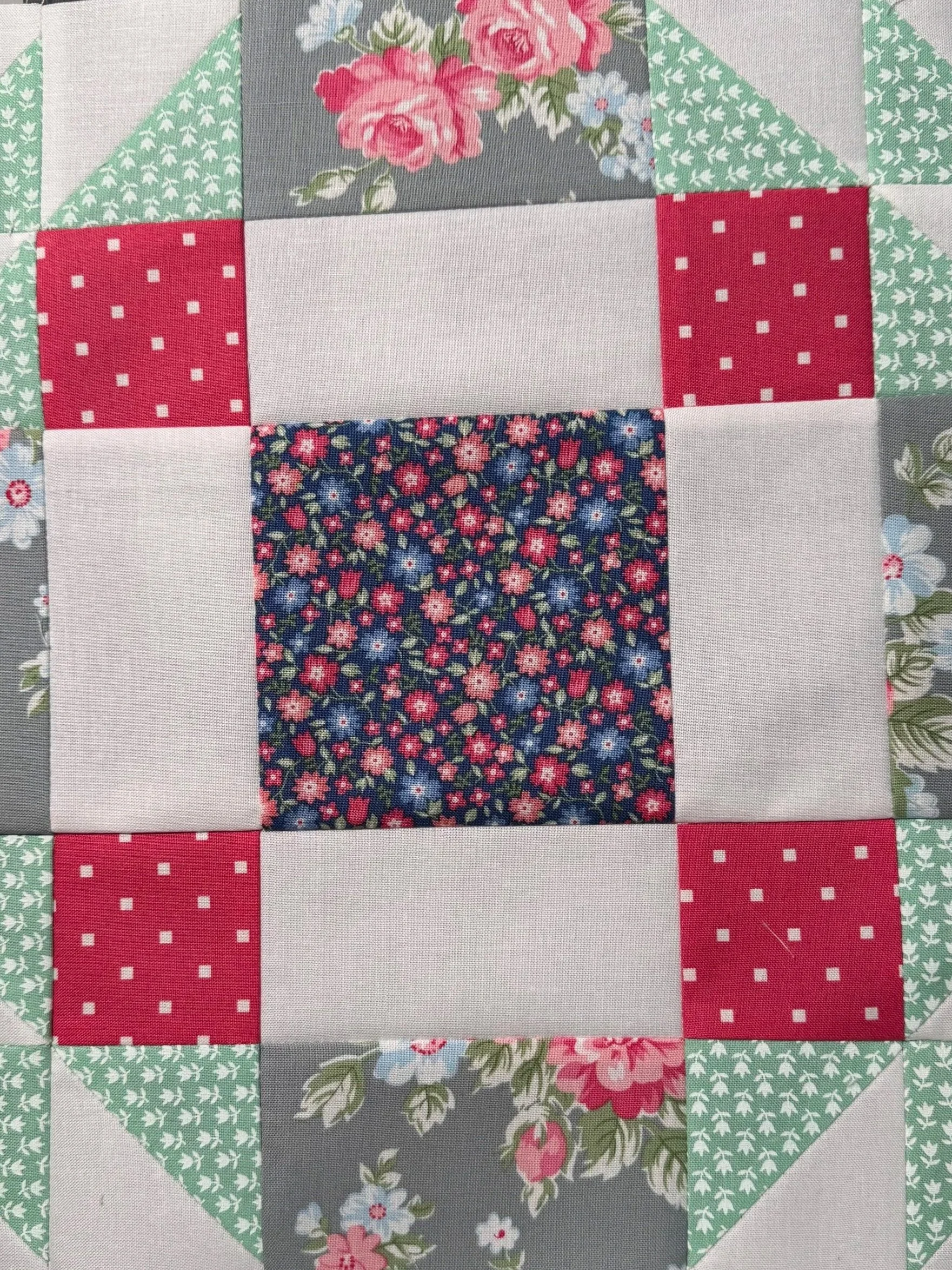 Floral patchwork quilt block in gray, mint green, red and navy fabrics. Explore the Quilting Notebook.