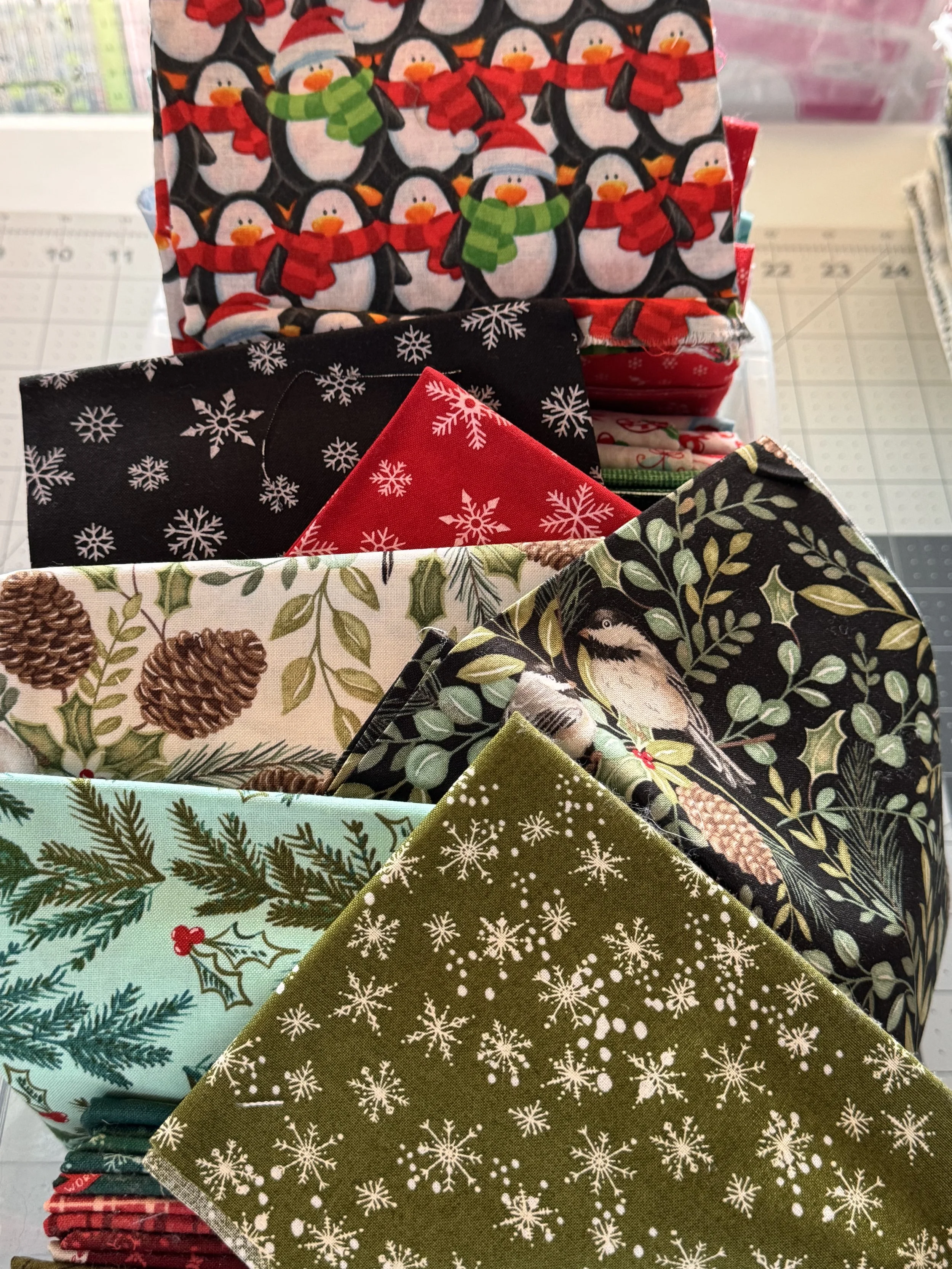 Assortment of colorful Christmas-themed cotton fabrics arranged for holiday sewing projects