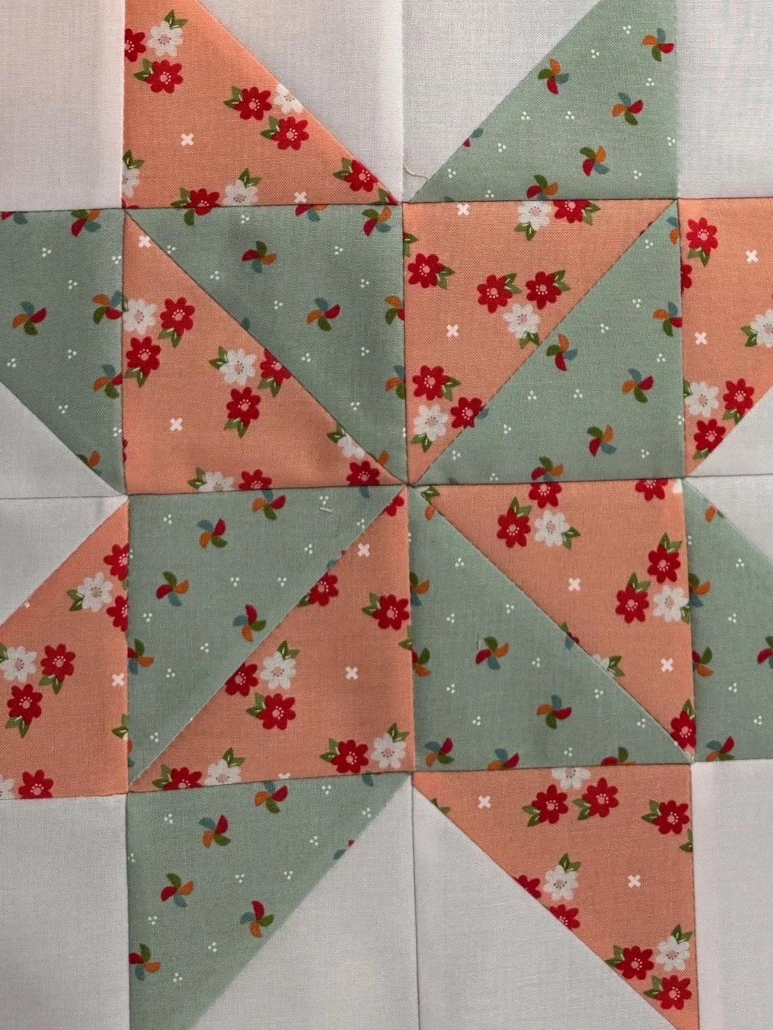 Traditional star quilt block featuring floral fabrics in peach and teal. Learn about Chris Cross Quilts & More.