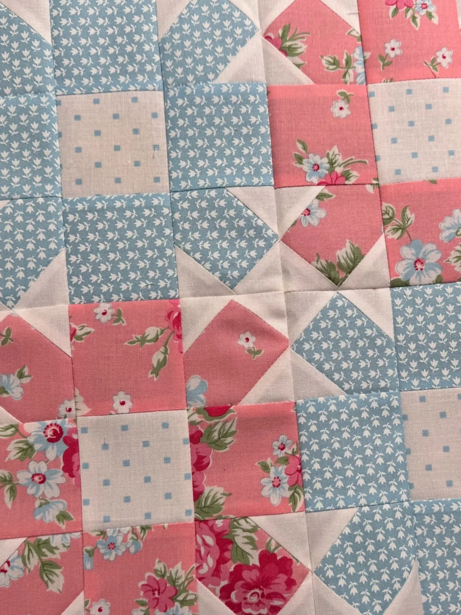 Four pink and blue patchwork quilt blocks arranged in a sampler. Explore quilting projects.