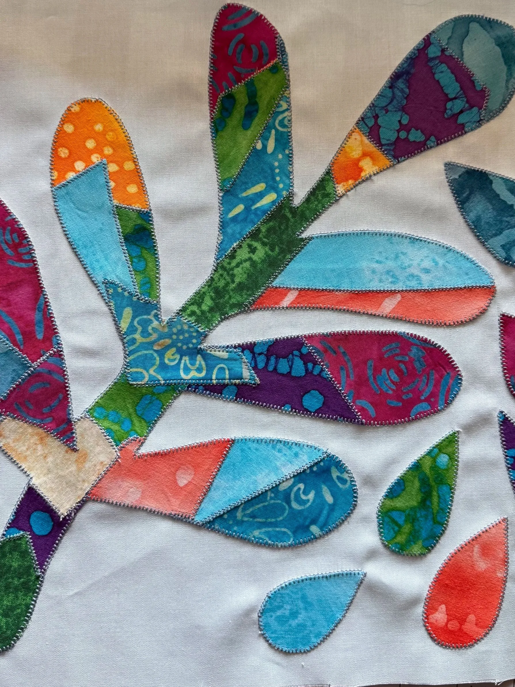Abstract multicolored batik appliqué with curved leaves and stitched details.