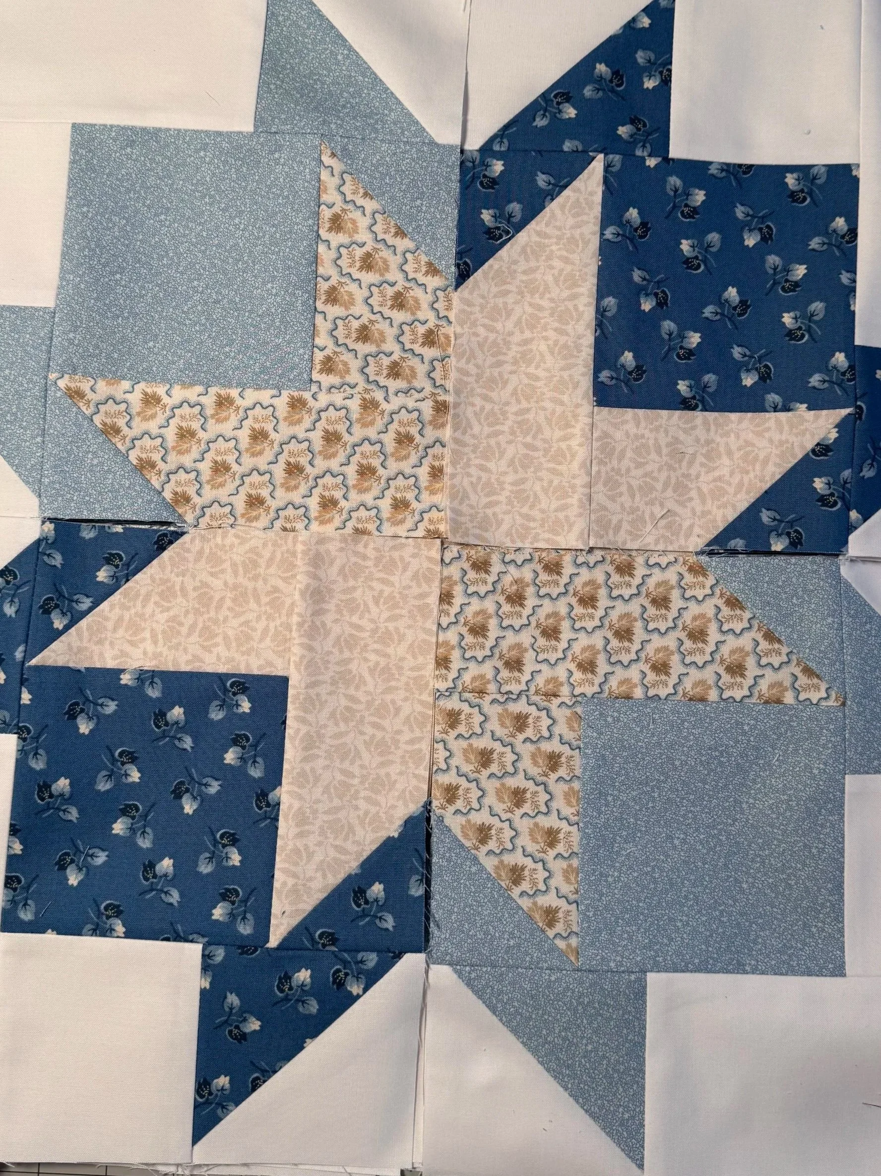 Blue and cream patchwork quilt featuring four large star blocks with floral and geometric fabric patterns