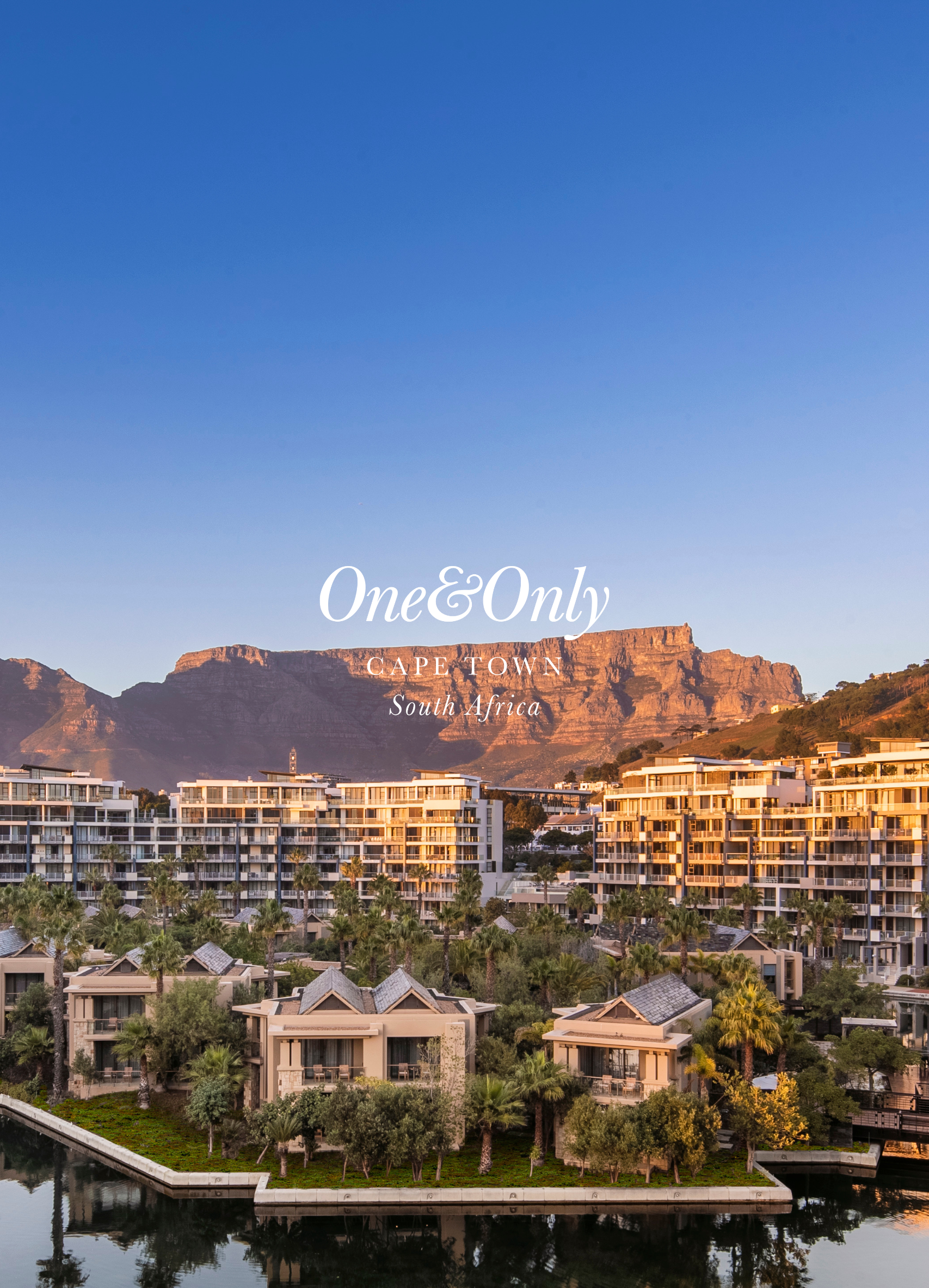 A scenic view of a cityscape in Cape Town, South Africa, with modern buildings, lush greenery, and the iconic flat-topped mountains in the background under a clear blue sky.