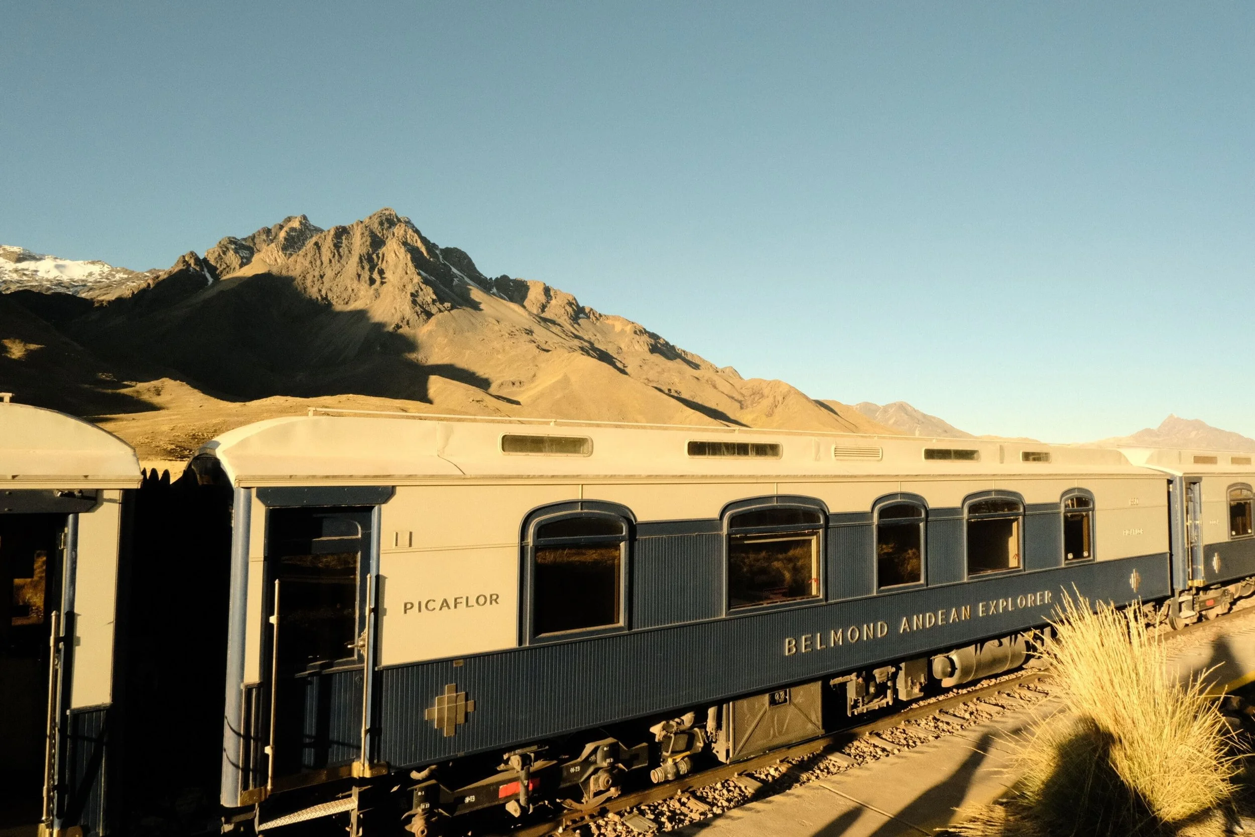 Train car with mountain background and clear blue sky.