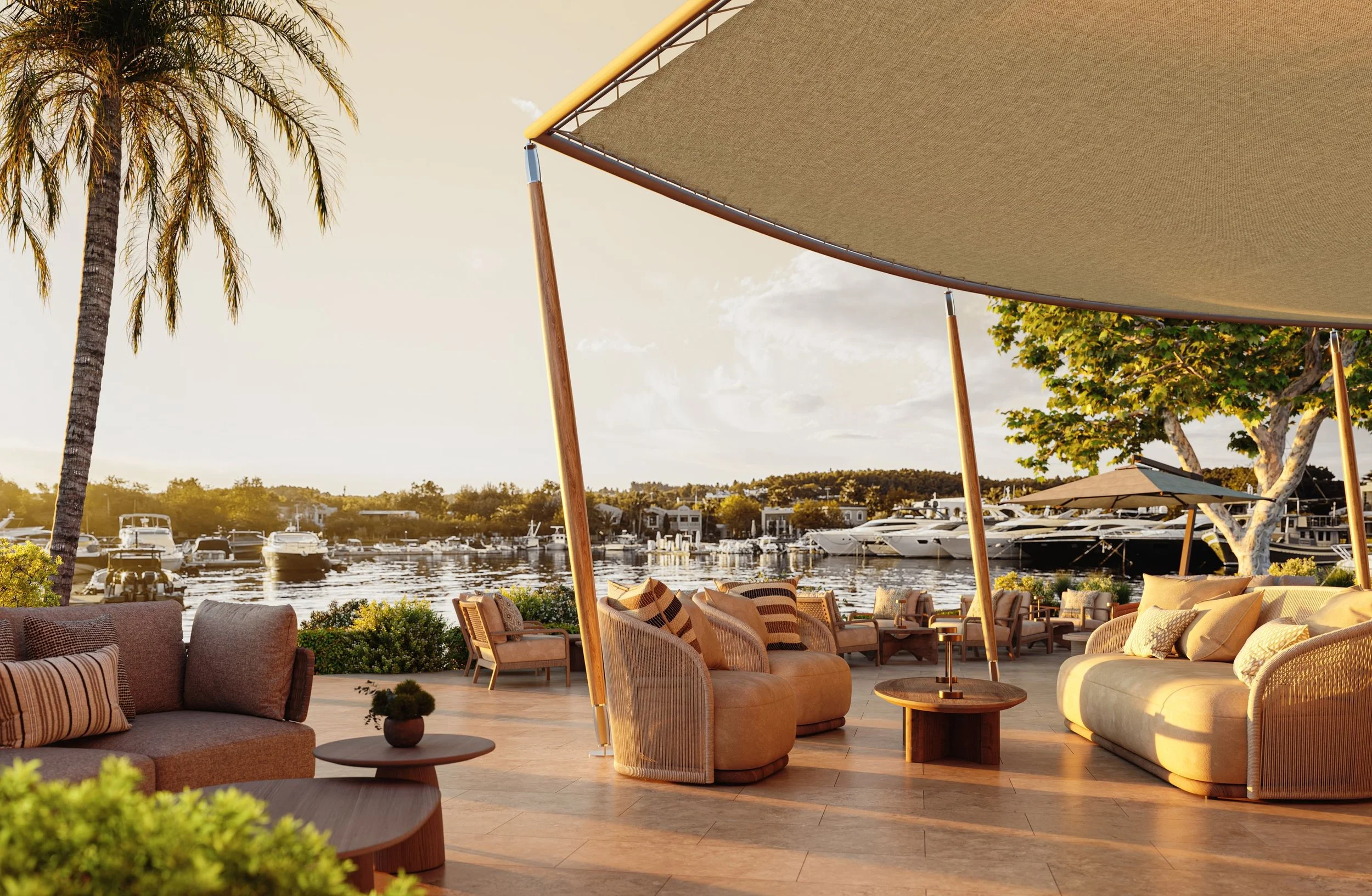 Outdoor seating area with beige and striped sofas, armchairs, and umbrellas near a marina with boats. Palm trees and a sunset sky are in the background.