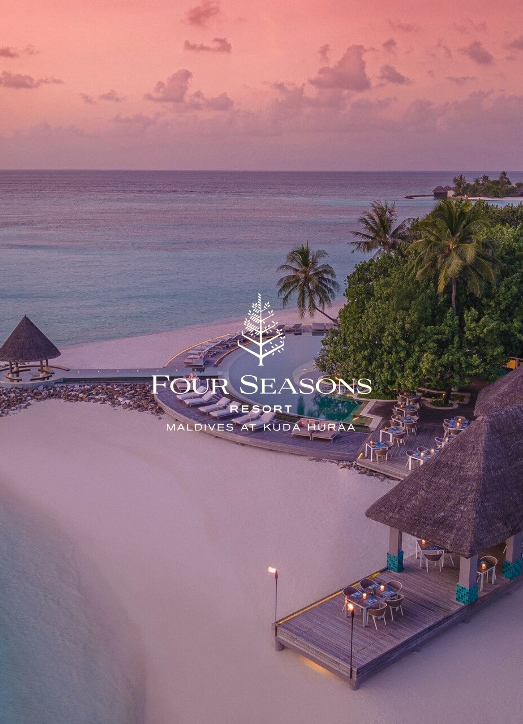 Overwater villas and a private pool at sunset at Four Seasons Resort Maldives at Kuda Huraa, with palm trees, tiki torches, and lounge chairs on the sandy beach.