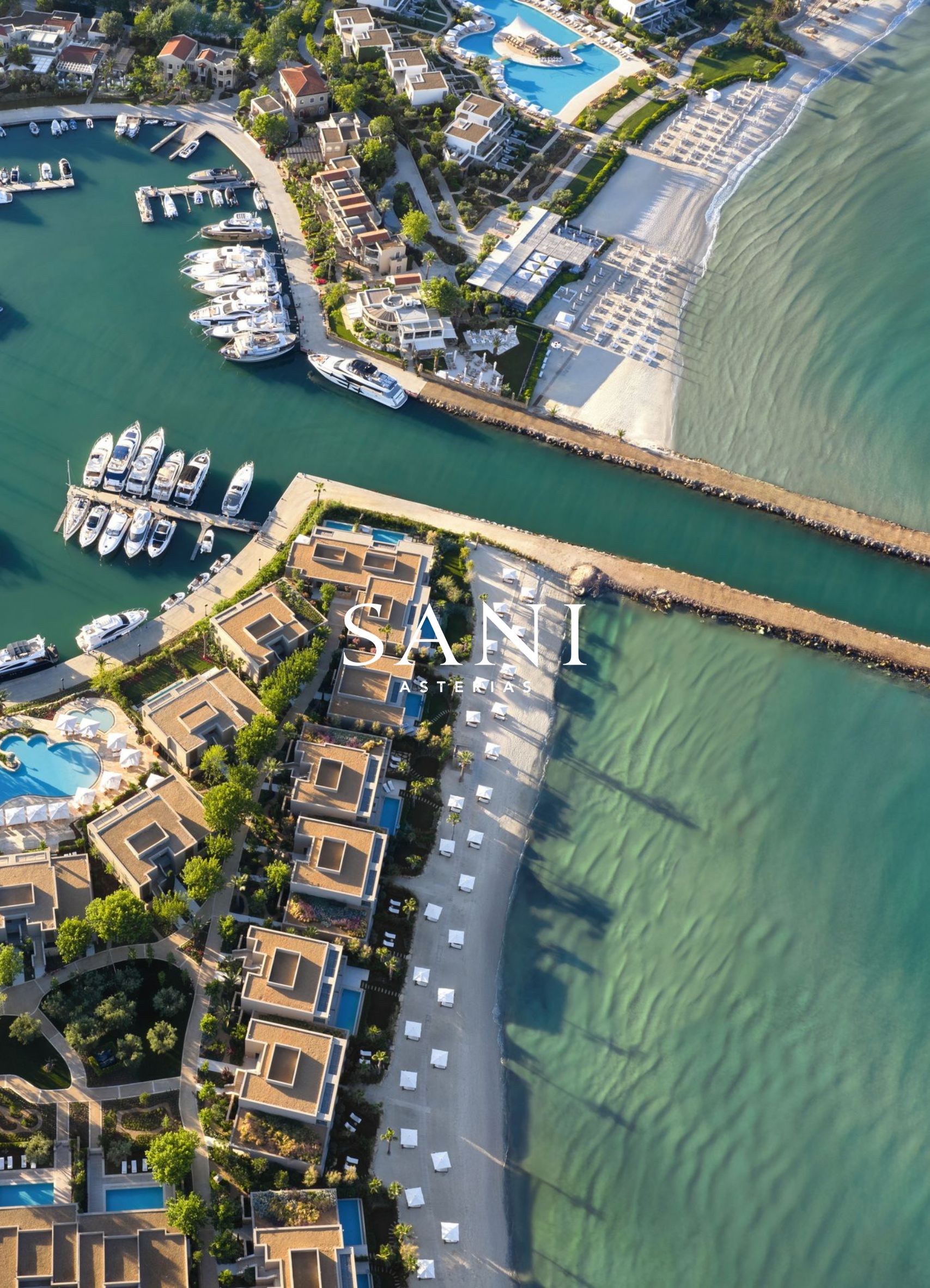 Aerial view of a coastal residential area with houses, a marina with boats, a sandy beach, a swimming pool, and a pier extending into the water.