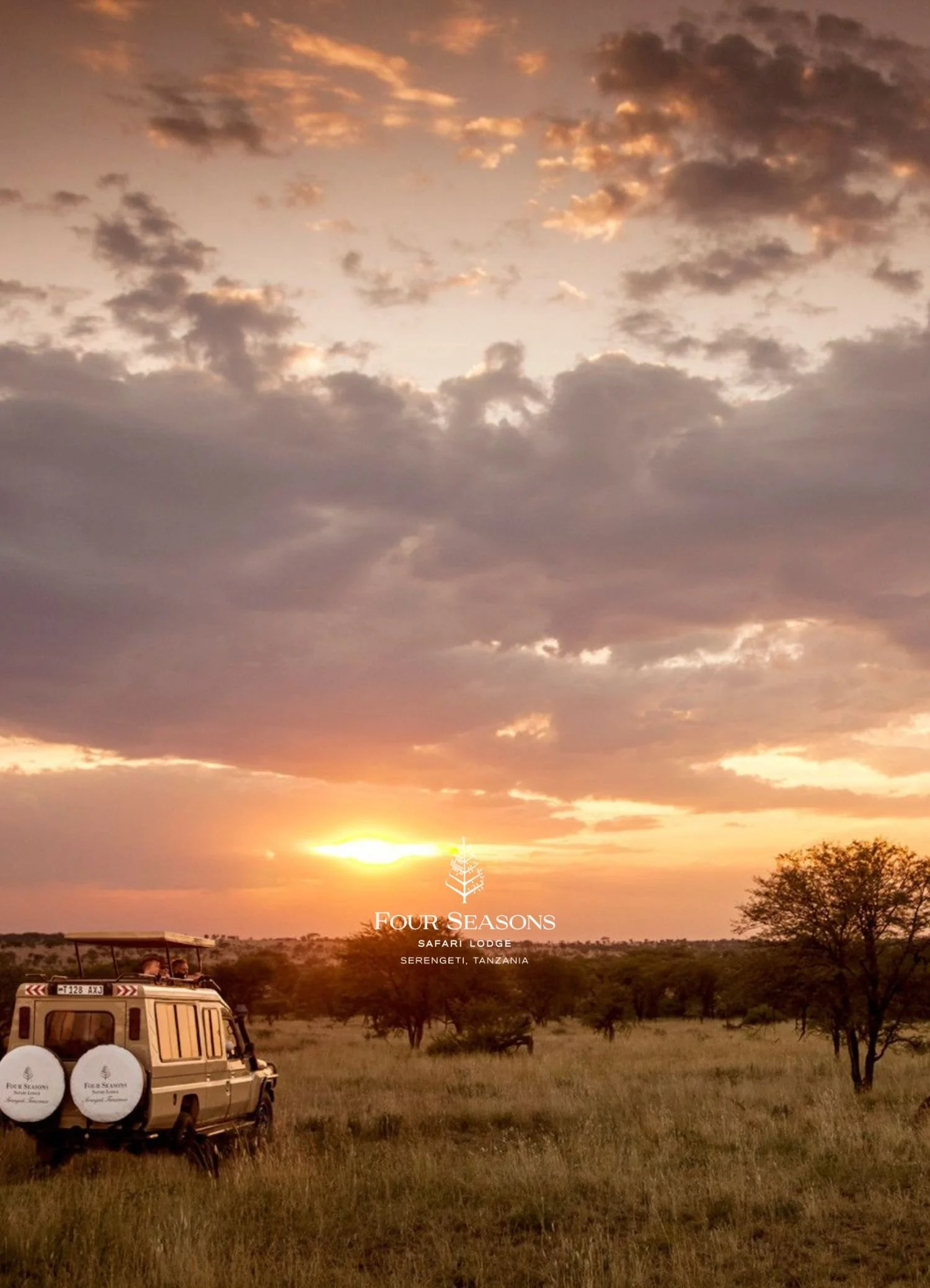 Sunset in Serengeti, Tanzania, with a safari vehicle and trees in the foreground, clouds in the sky, and the logo of Four Seasons Safari Lodge.