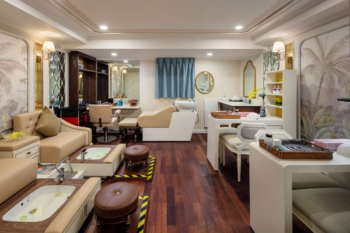 A spa room with massage chairs, pedicure stations, and relaxing decor, including palm tree murals and soft lighting.