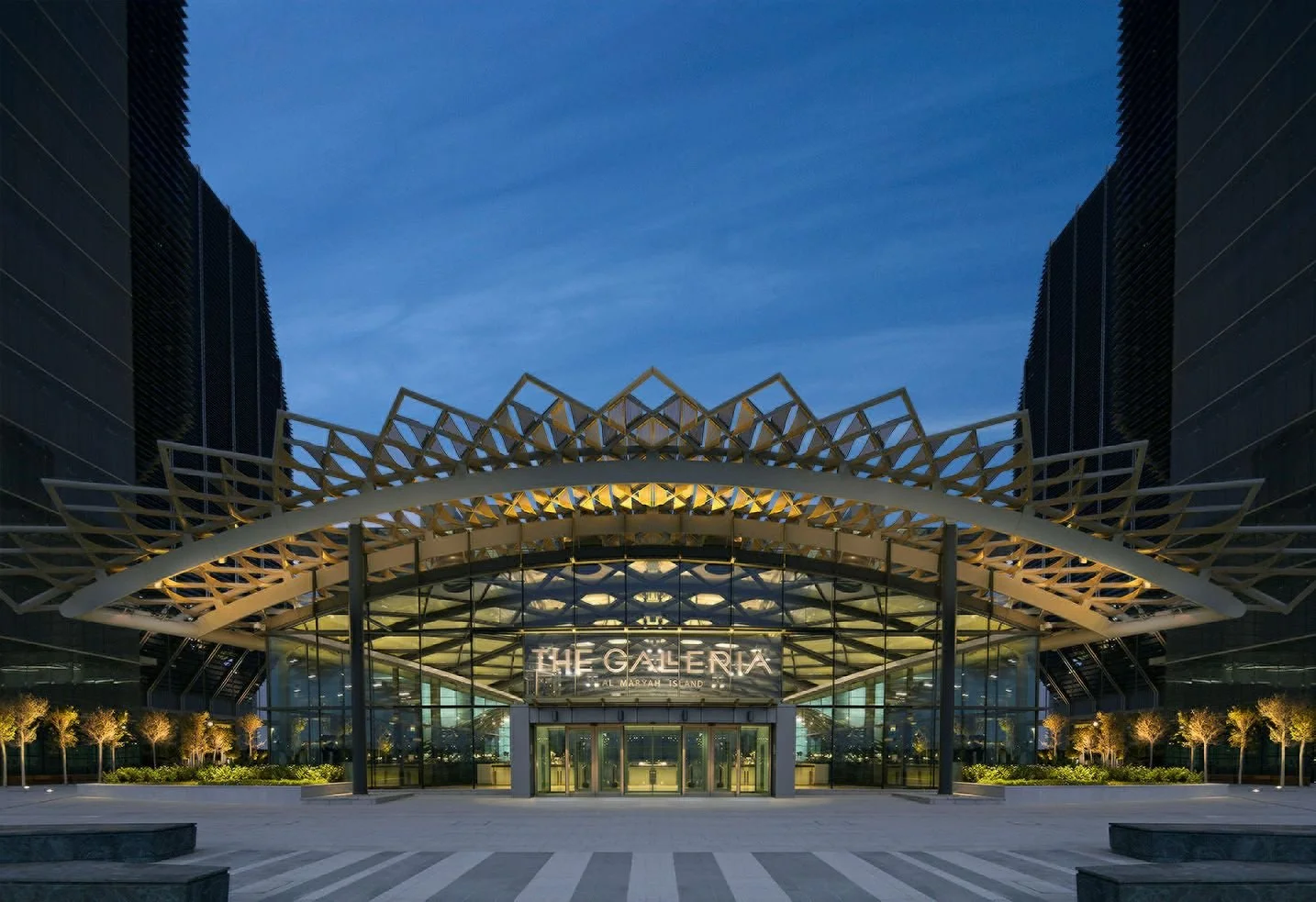 The entrance of The Galleria shopping mall at evening with illuminated sign and modern architectural design.