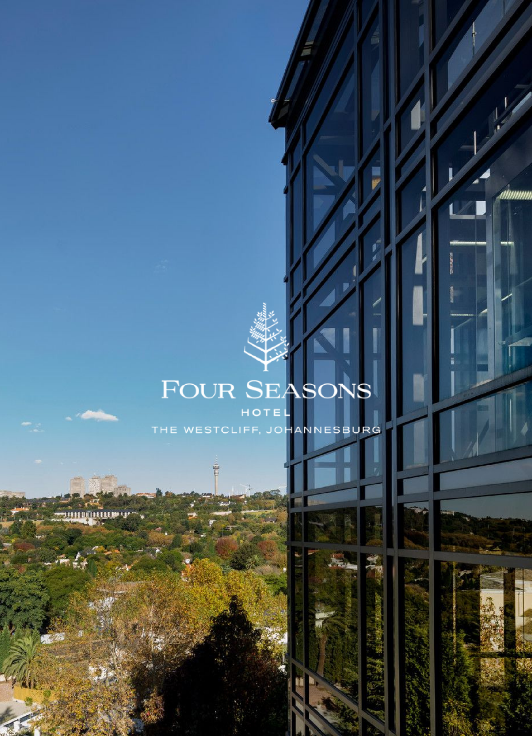 A photo of a modern glass building with a cityscape and clear blue sky in the background, with the words 'Four Seasons Hotel, The Westcliff, Johannesburg' written on it.