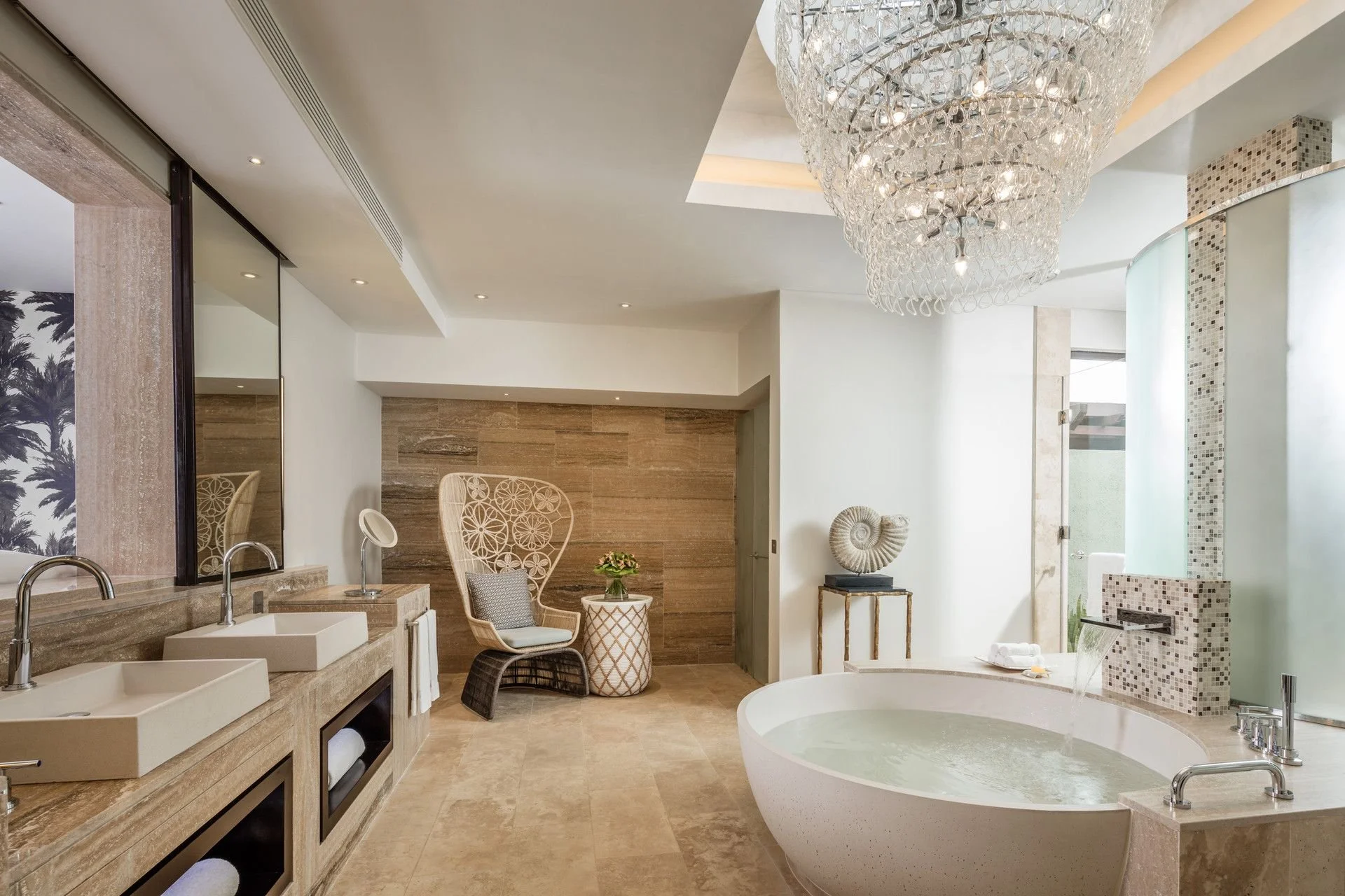 Modern bathroom with double sinks, a freestanding bathtub, a chandelier, and decorative wall art.