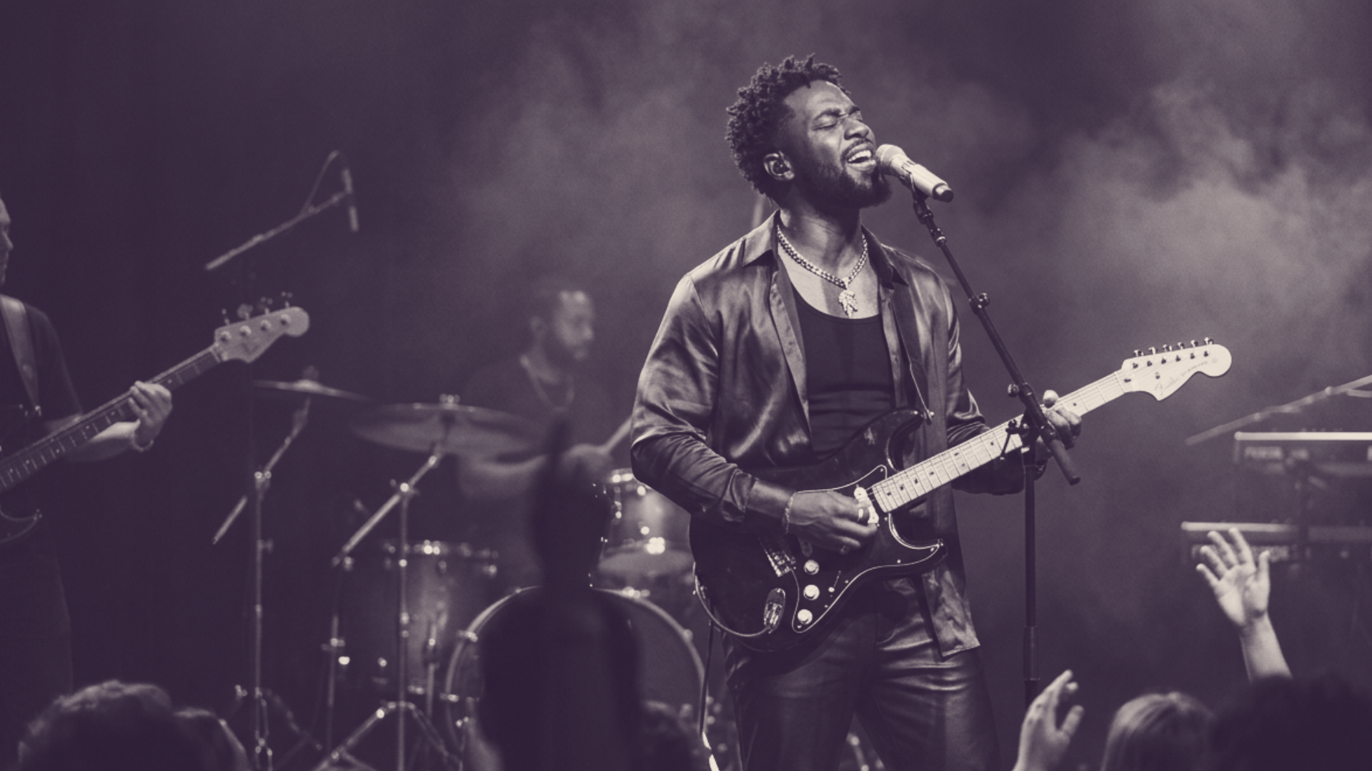 image of musician on a stage with an electric guitar singing into a microphone