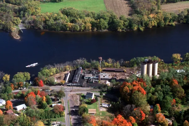 Aerial view of a small town with colorful autumn trees, a river, and industrial buildings.