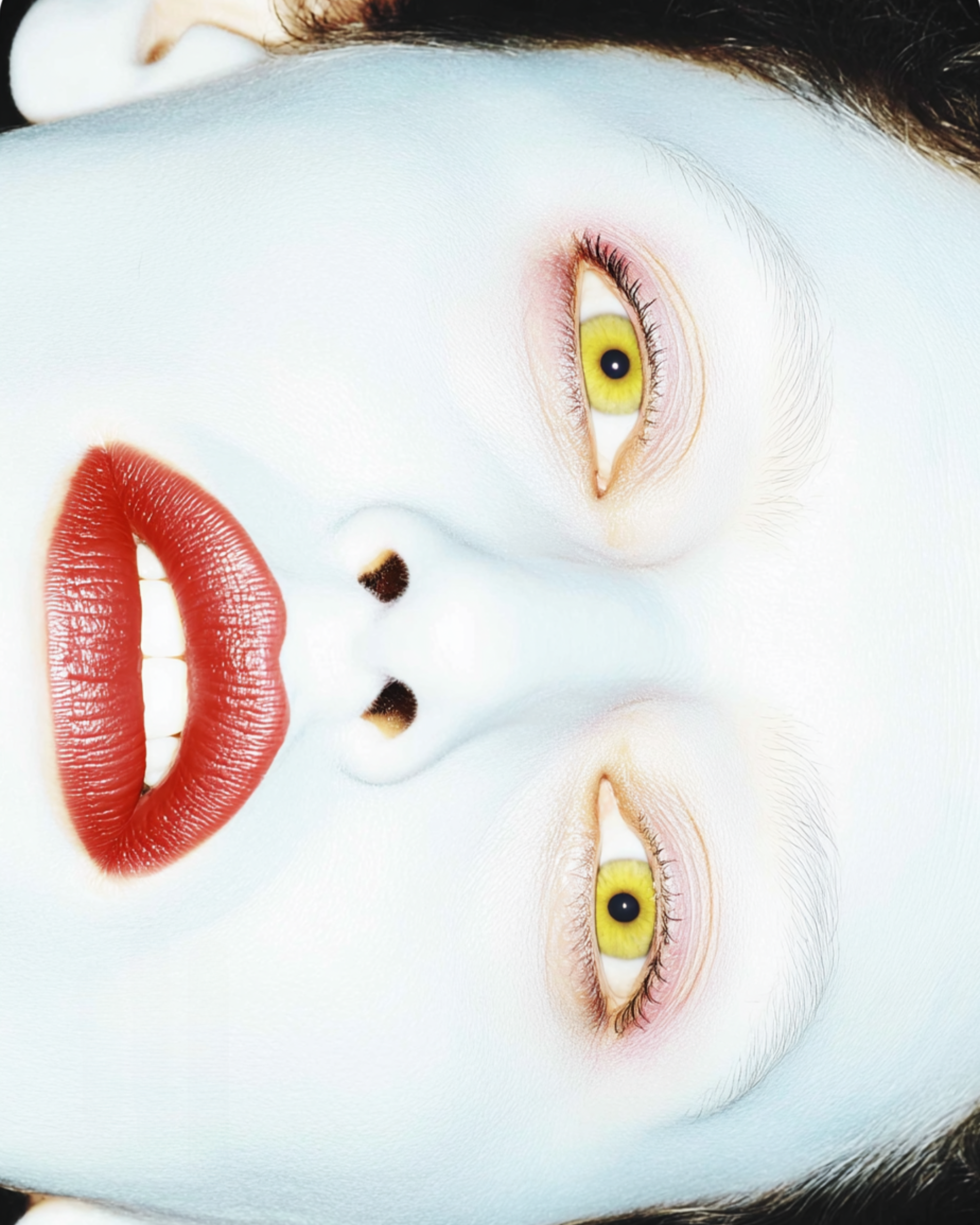 An artistic photo of a person's face with their eyes and lips reversed, showing yellow eyes and red lips, creating a surreal, mirrored effect.