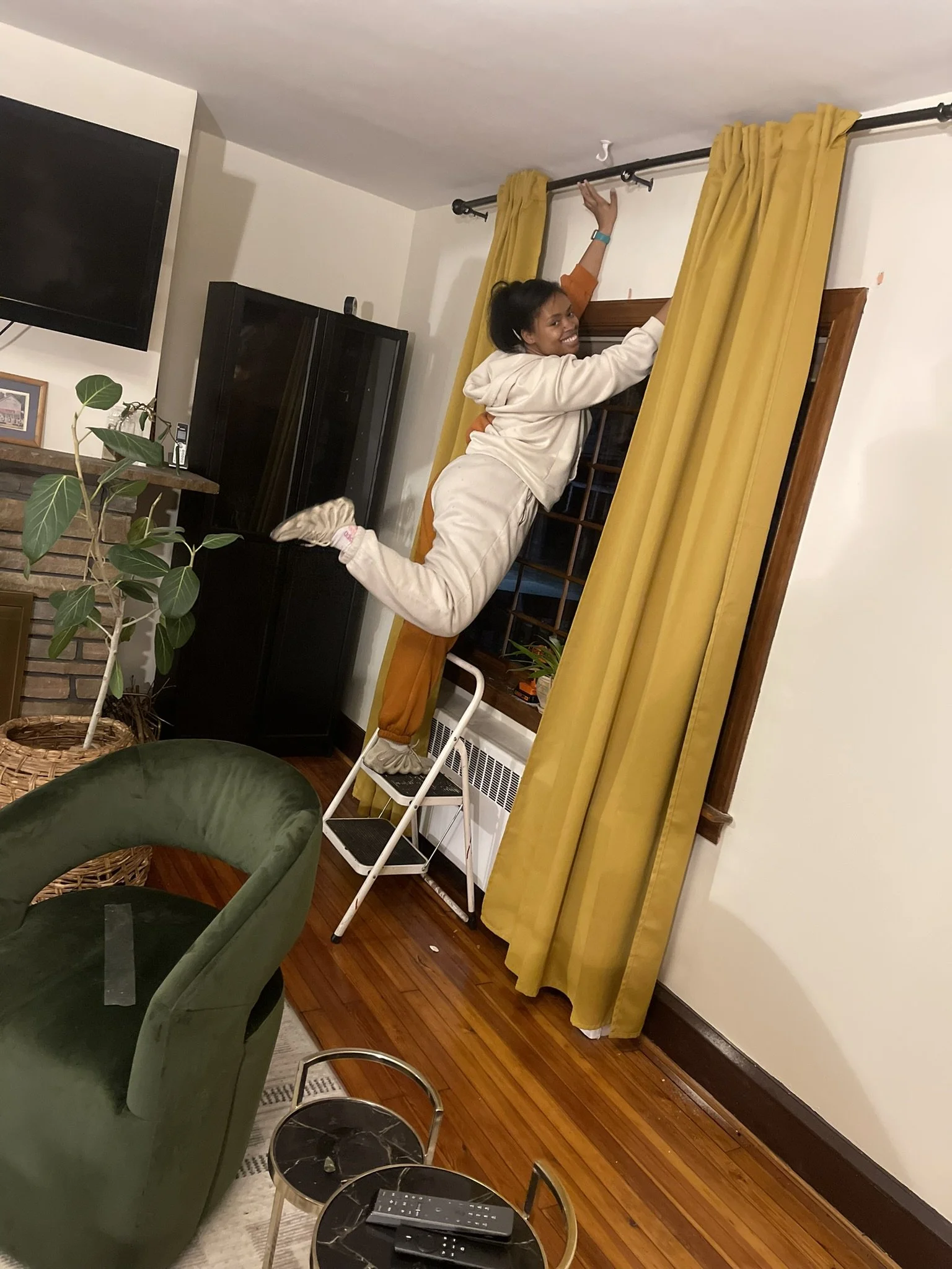 Omoye, founder of Honey, You’re Home, styling a living room with yellow curtains, vintage green armchair, and houseplants