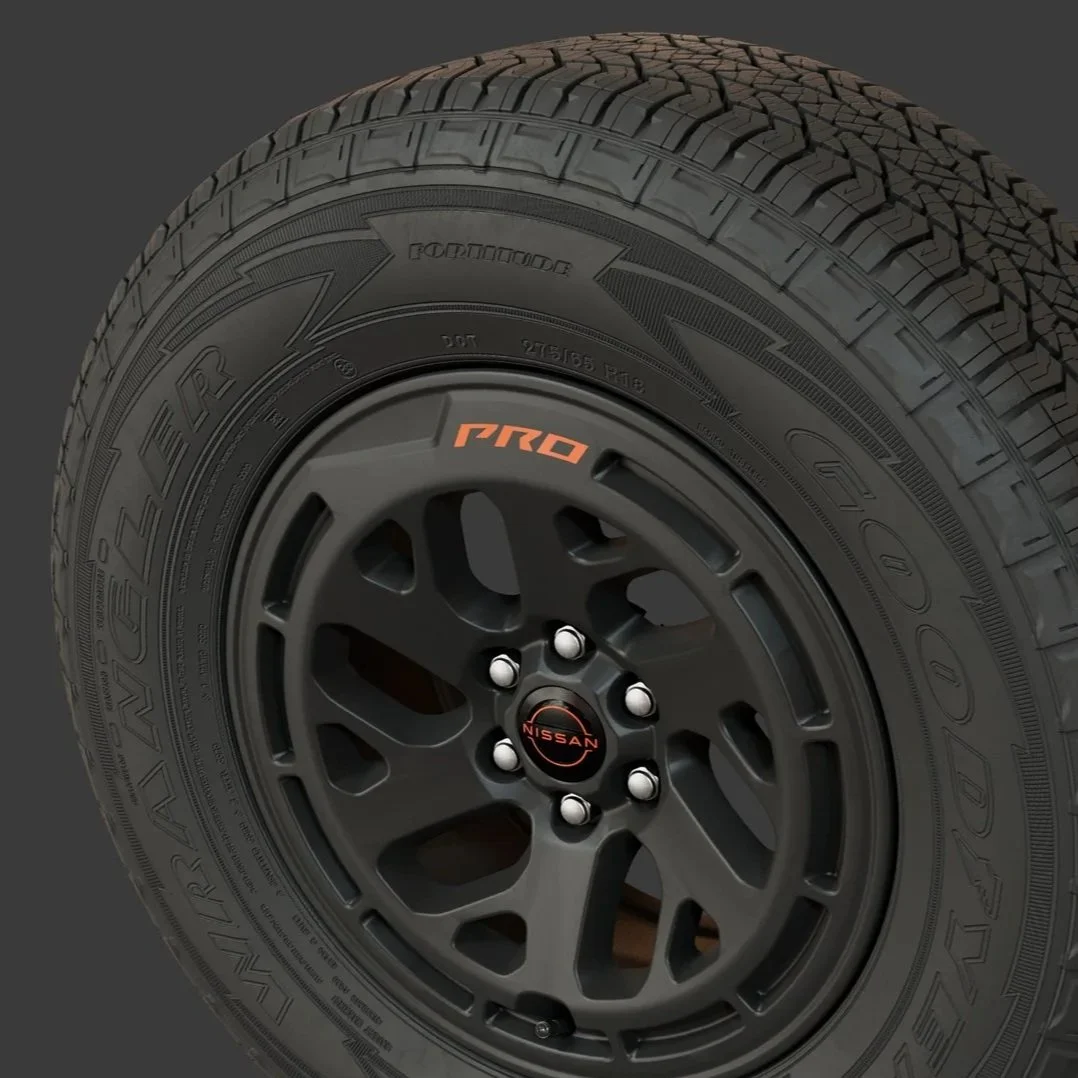 A close-up of a black Nissan vehicle wheel with a Goodyear Wrangler tire, featuring a black rim labeled 'PRO' in orange.
