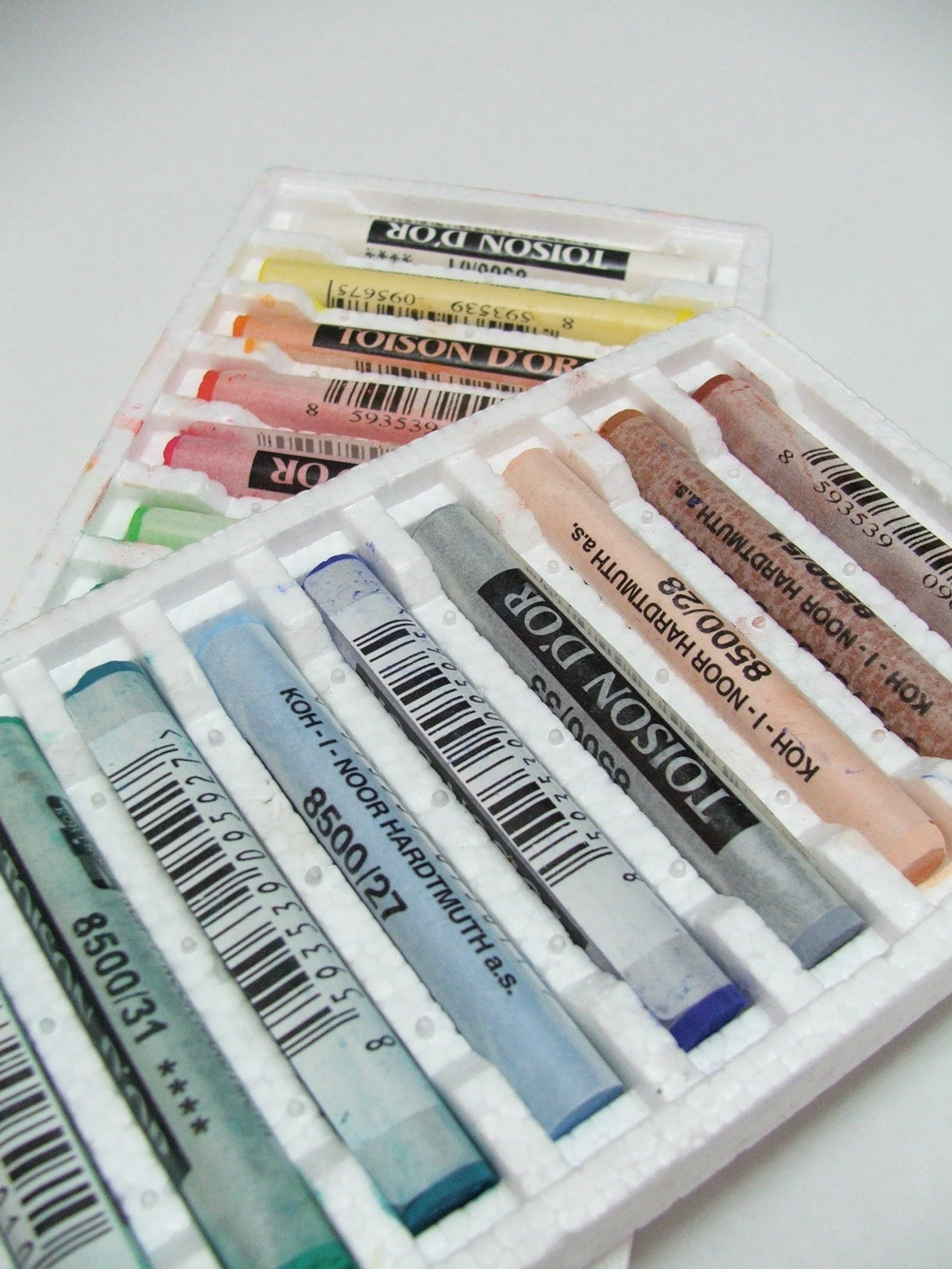 A white plastic container with individually packaged tubes of various colors, labeled with barcodes and printed text indicating it contains medicine or chemicals.