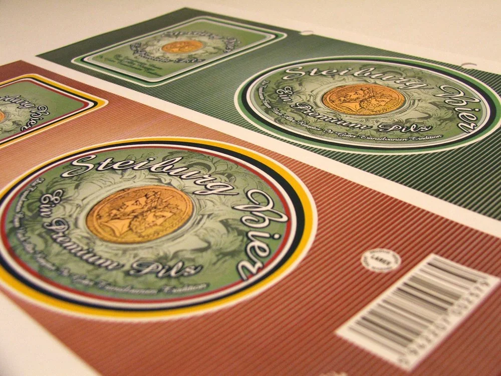 Close-up image of three different-sized boxes of Steiburg Bier labels, with the labels showing the brand name, logo, and barcode.
