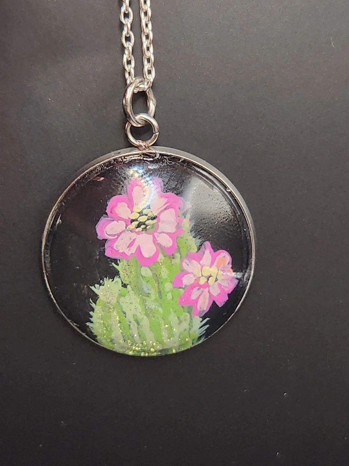 Pink cactus flower art pendant hanging from a silver-tone chain. Chain not included.