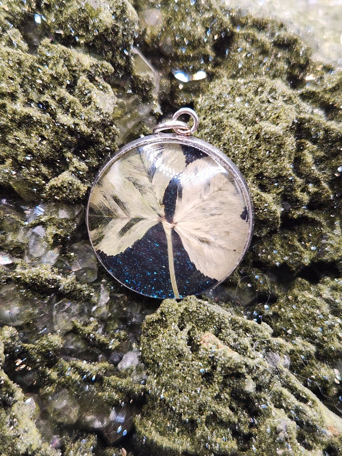 Naturally Unique N003: real four-leaf clover pendant with blue glitter on a crystal display. Display not included.
