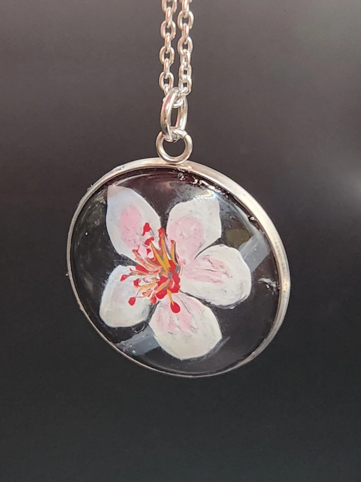 Pink cherry blossom art pendant hanging from a silver-tone chain. Chain not included.
