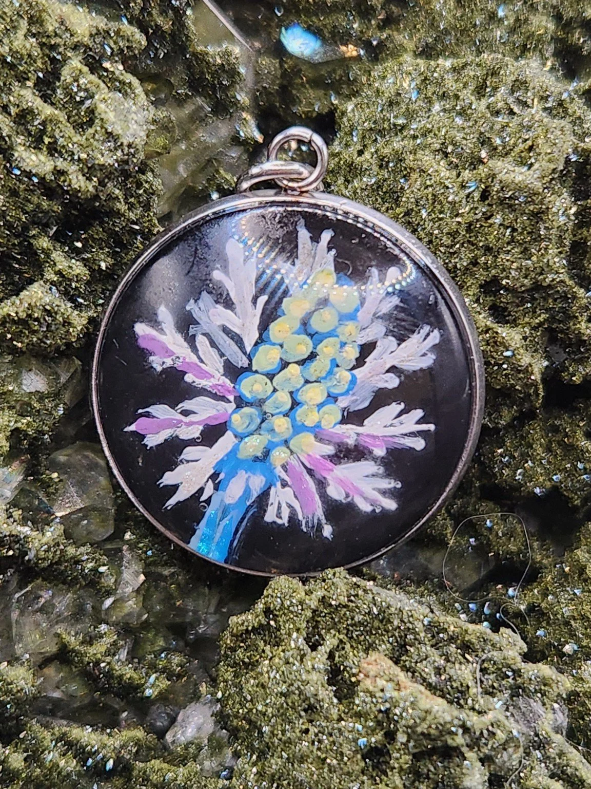Eryngium sea holly flower art pendant displayed among green crystals. Crystal display and props not included.