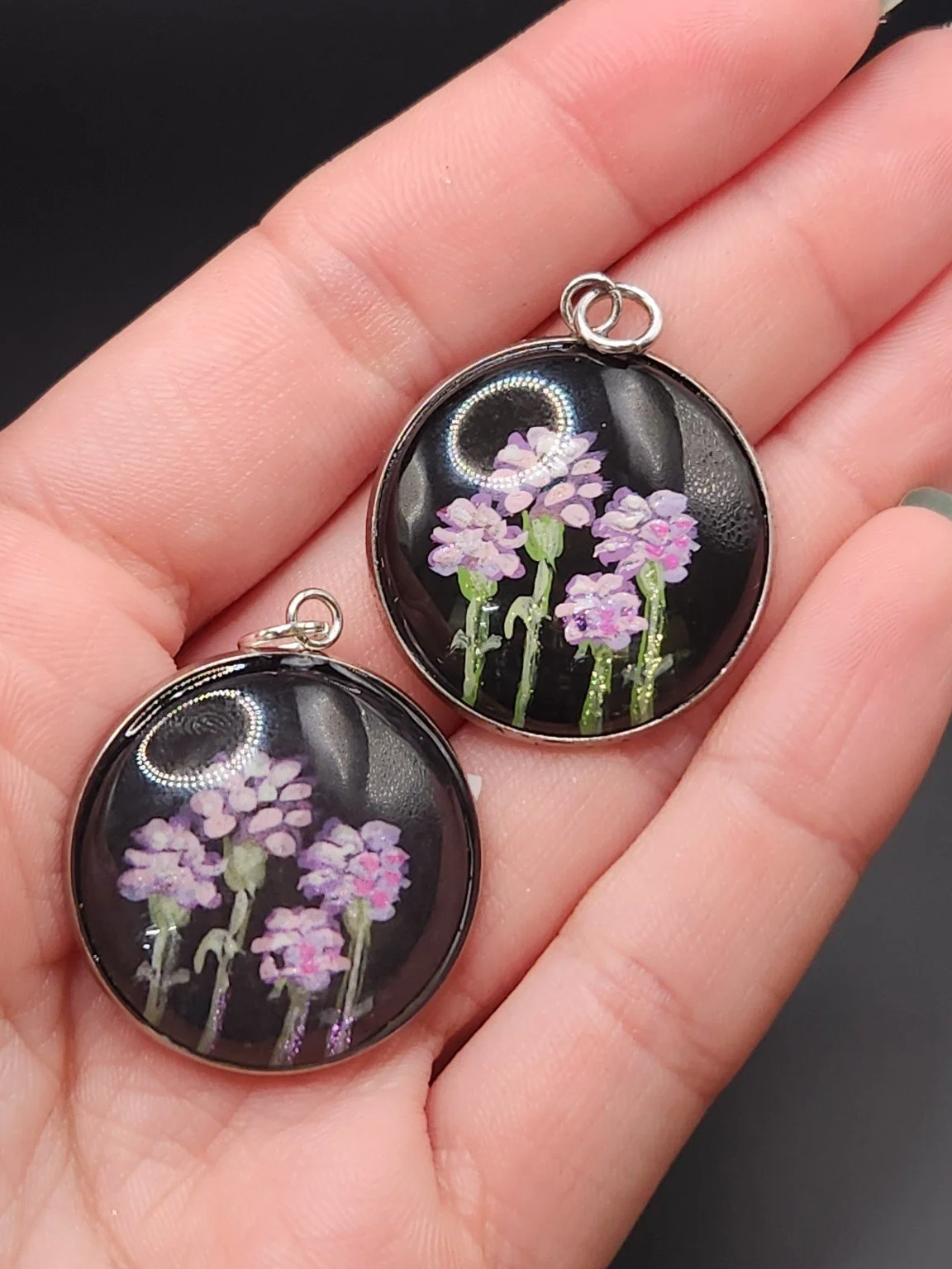 Carnation pendant comparison held in a hand: the hand-painted original is at the top right, and the printed reproduction is at the bottom left.
