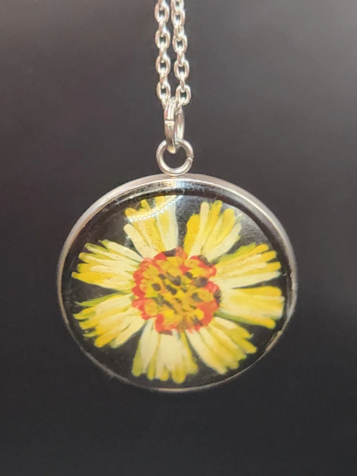 Yellow coreopsis flower art pendant hanging from a silver-tone chain against a dark background. Chain not included.