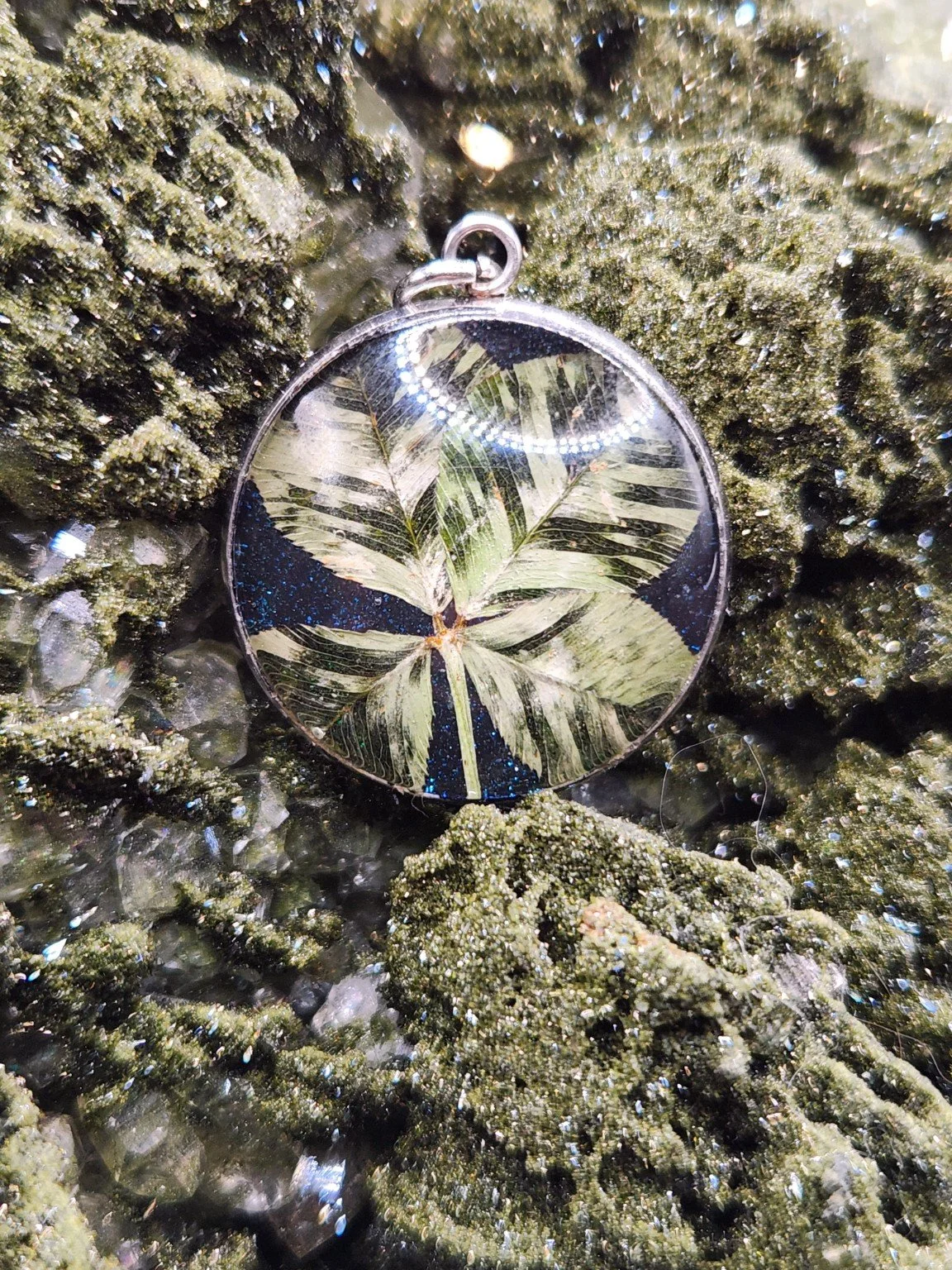 Perfectly Imperfect I004: patterned real clover pendant with blue glitter on a crystal display. Display not included.