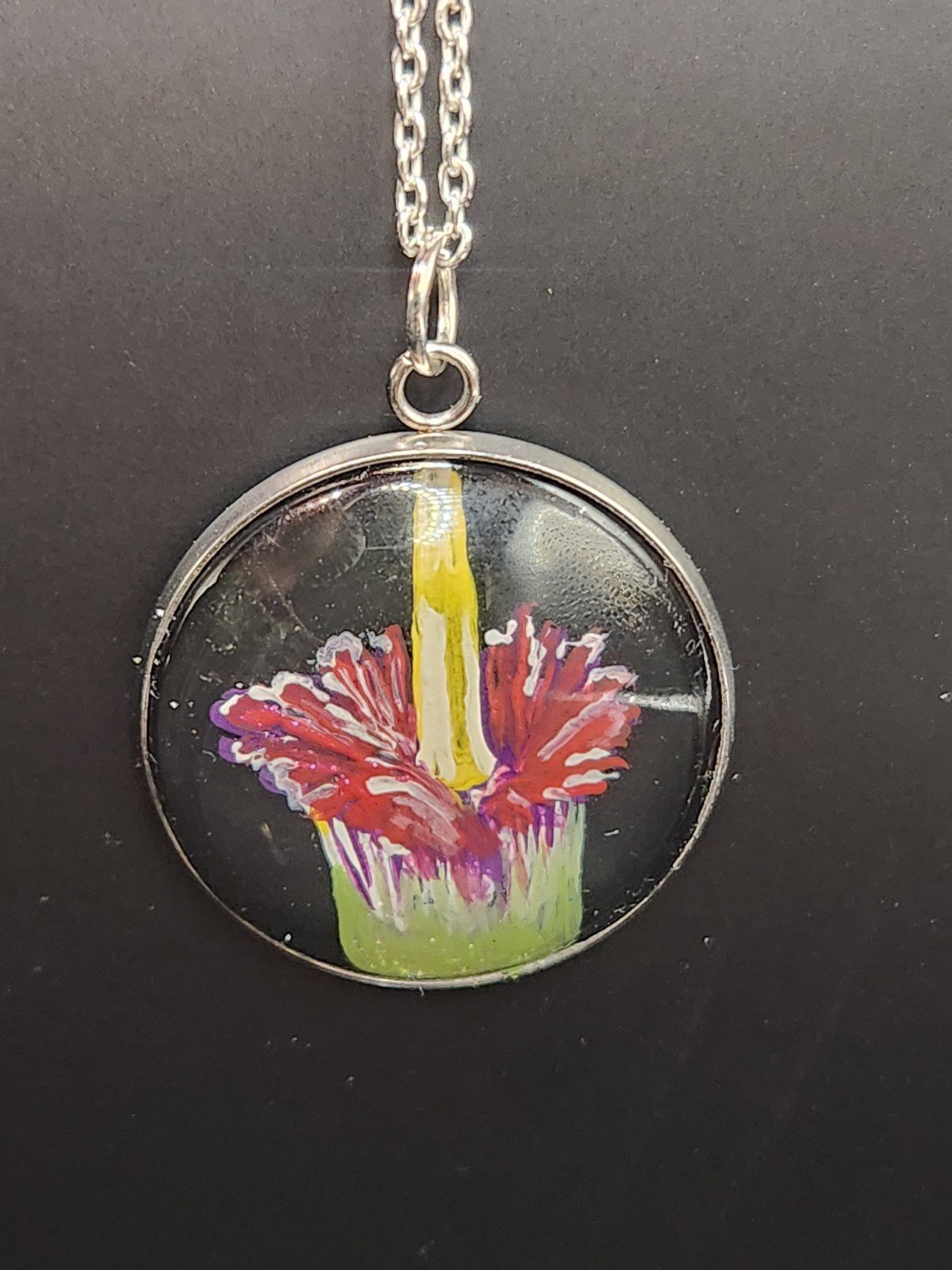 Corpse flower art pendant shown on a silver-tone chain against a dark background. Chain not included.