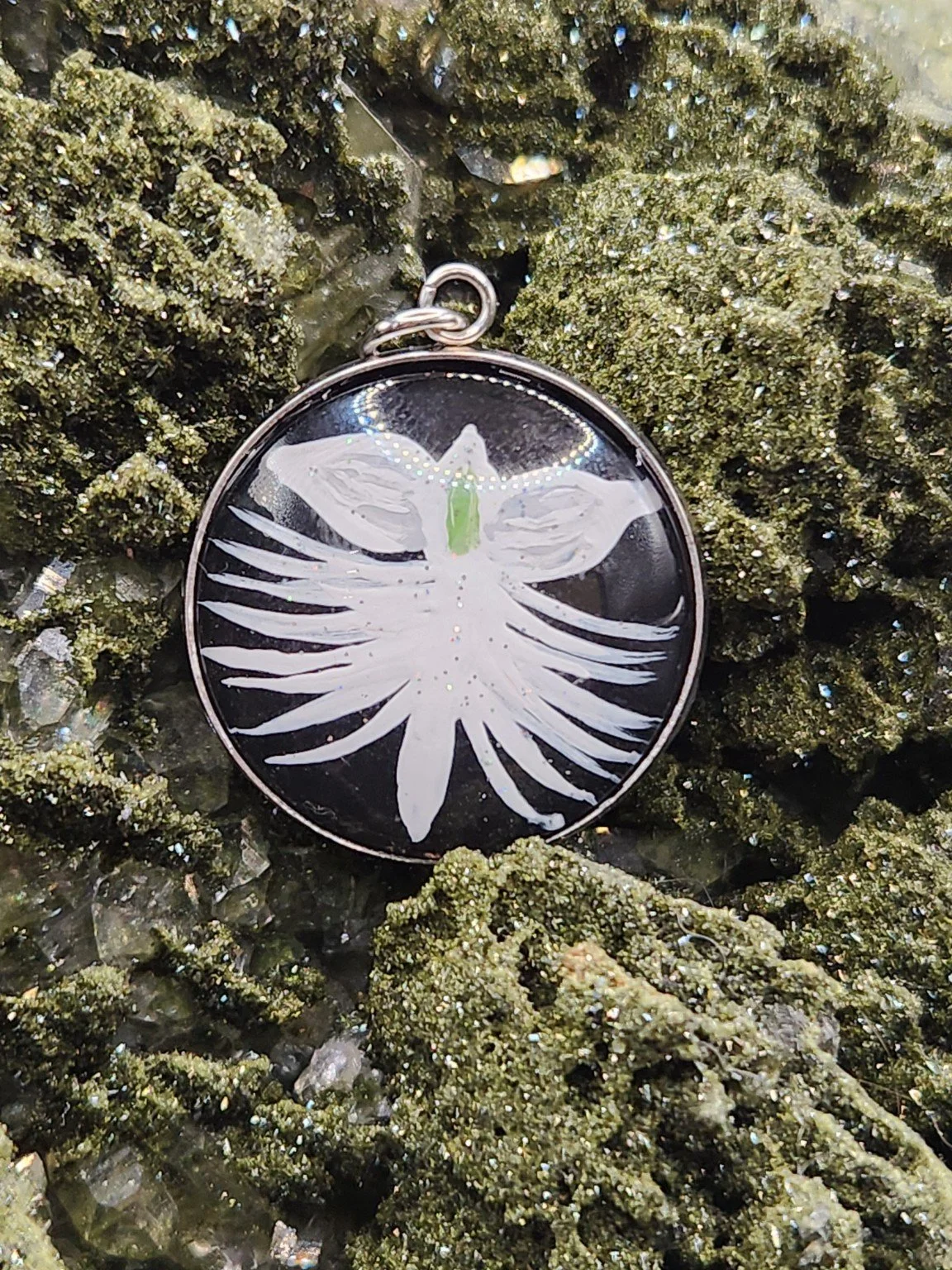 White dove orchid flower art pendant displayed among green crystals. Crystal display and props not included.