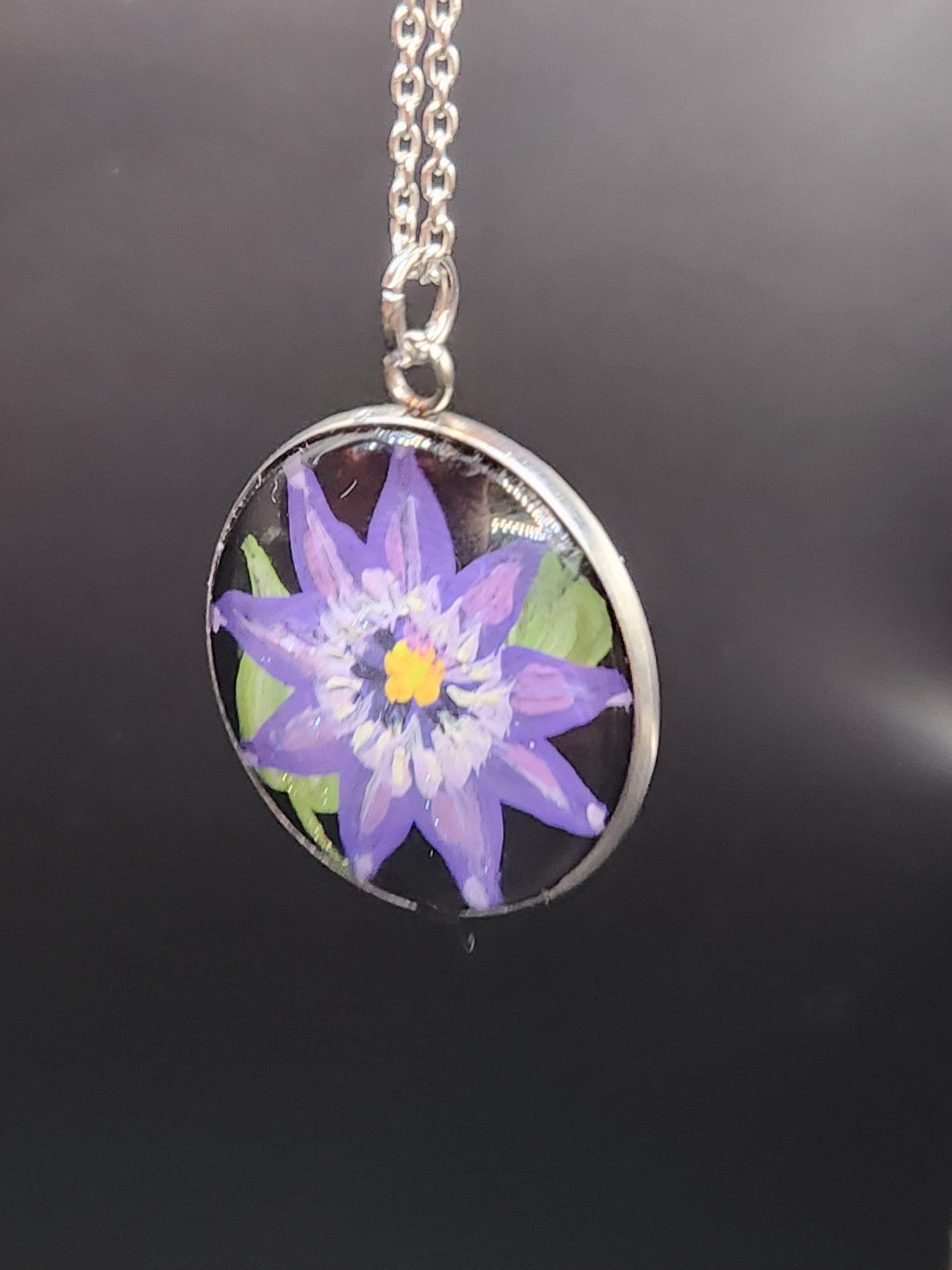 Purple clematis flower art pendant hanging from a silver-tone chain. Chain not included.