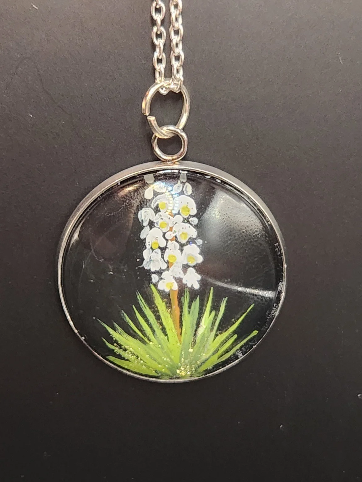 White yucca flower art pendant hanging from a silver-tone chain. Chain not included.
